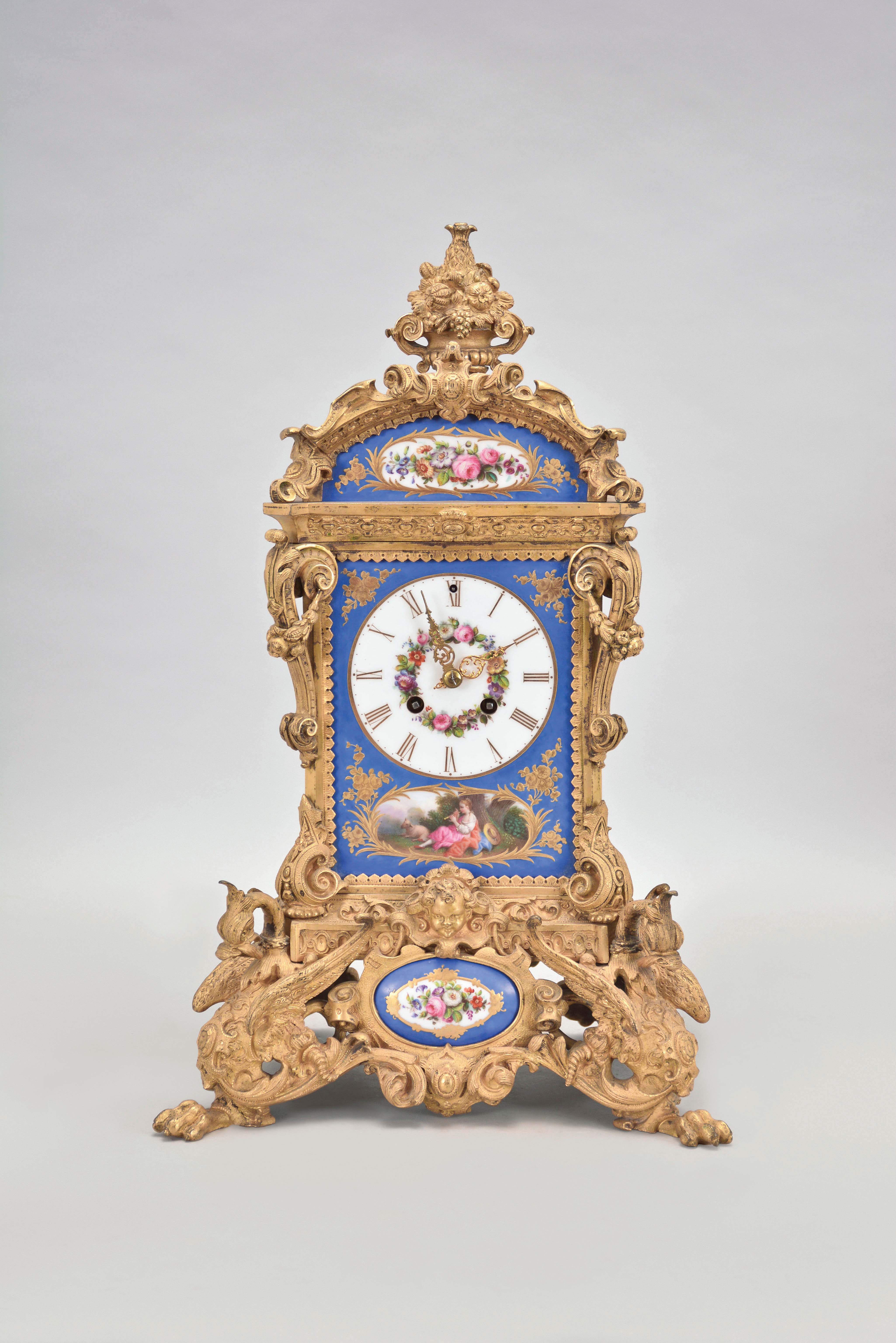Grohe, a Paris, an ornate, renaissance revival, gilt bronze and porcelain mounted mantel clock, the case resting on gryphon and scroll feet, with dome top and fruit filled urn finial, and replete with rococo and renaissance revival ornament, the panels in the manner of Jacob Petit, with blue ground, and gilt bordered, floral vignettes, the front with a shepherdess in a landscape playing a flute below the roman numeral dial with floral wreath, fancy gilt hands, 8 day, two train pendule de Paris movement striking on a bell — Antique Clocks Price Guide