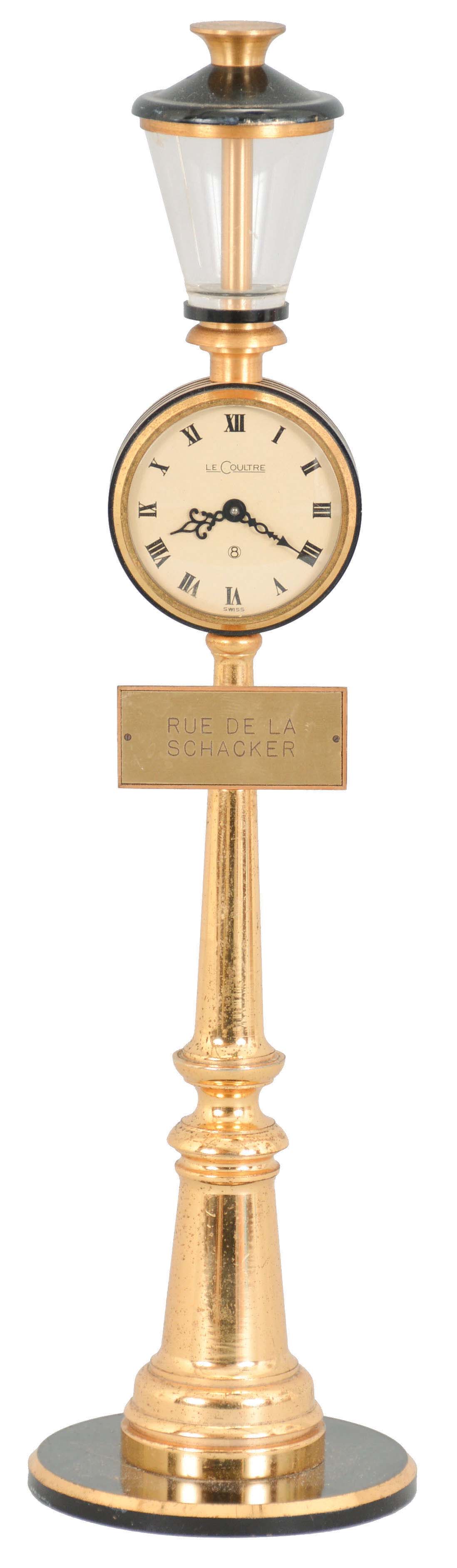 LeCoultre, Switzerland, "Rue de la Paix" desk or table clock, the turned, gilt, lamp post form case with 8 day, timepiece movement, Roman numeral white painted dial, and fancy blued steel hands, the Rue de la Paix sign professionally changed to read "Rue de la Schacker" for a previous owner — Antique Clocks Price Guide