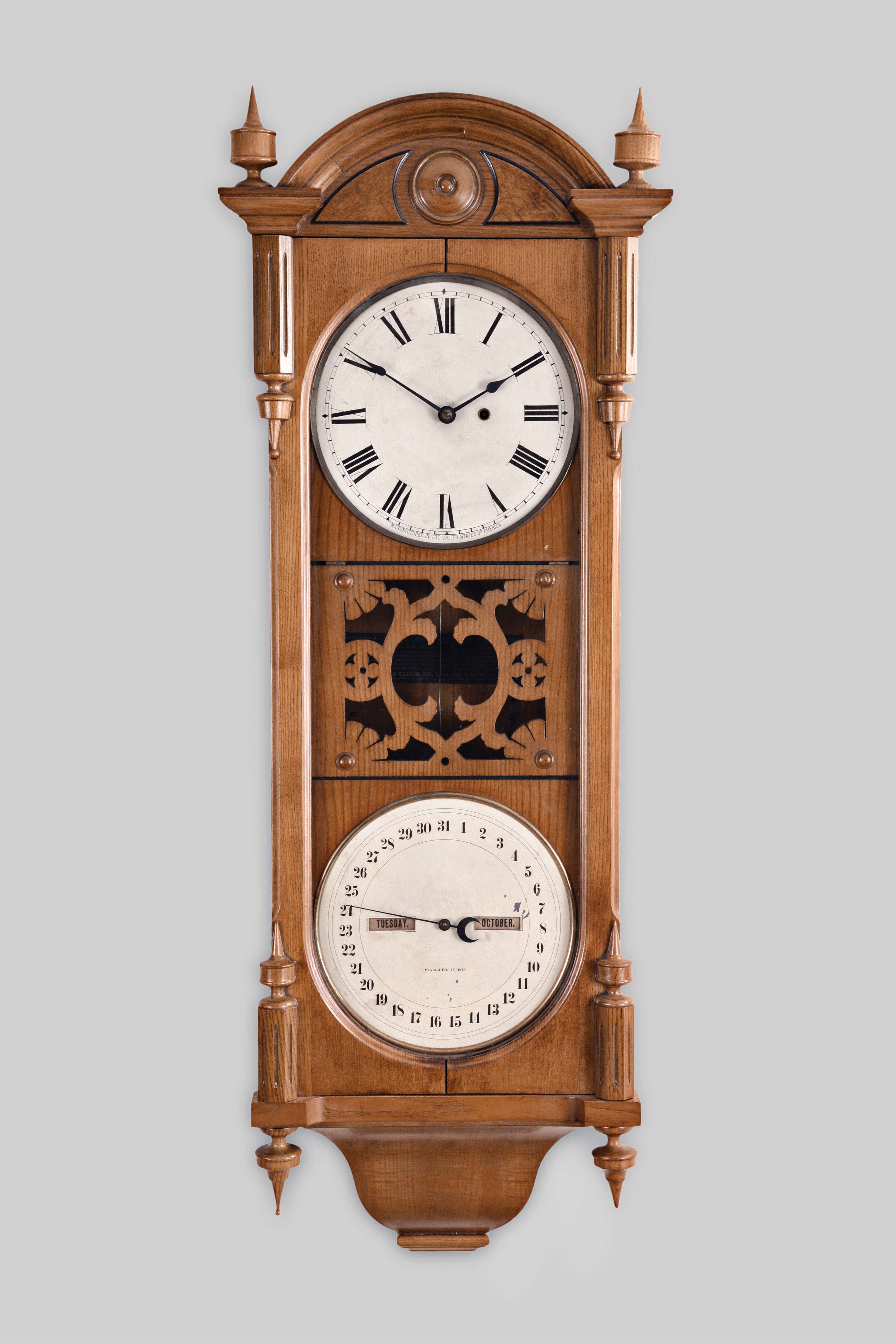Seth Thomas Clock Co., Thomaston, Conn., "Office Calendar No. 10" hanging clock with a weight driven, 8 day, timepiece movement and a R. T. Andrews patented perpetual calendar mechanism in an oak case with burl walnut accents. — Antique Clocks Price Guide
