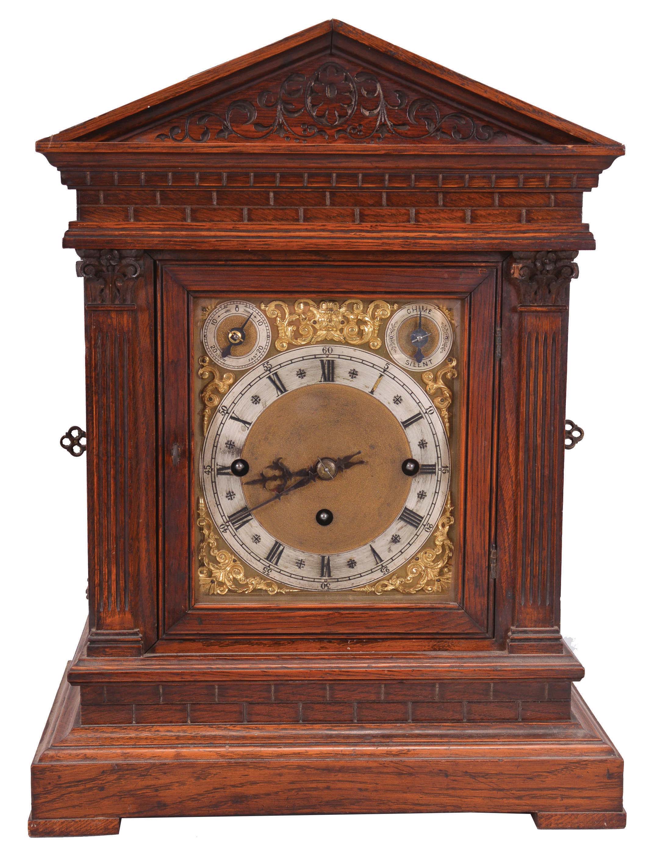 Winterhalder &amp; Hofmeier, Schwarzenbach, Germany, bracket clock, 8 day, time and strike with Westminster chime playing on four gongs, triple fusee movement in an oak architectural case with fluted pilasters, frieze meant to resemble ashlar, tympanum with carved floral design, brass dial plate with applied cast spandrels, silvered chapter ring with Roman numerals, subsidiary rate adjustment and chime / silent dials, blued steel hands. — Antique Clocks Price Guide