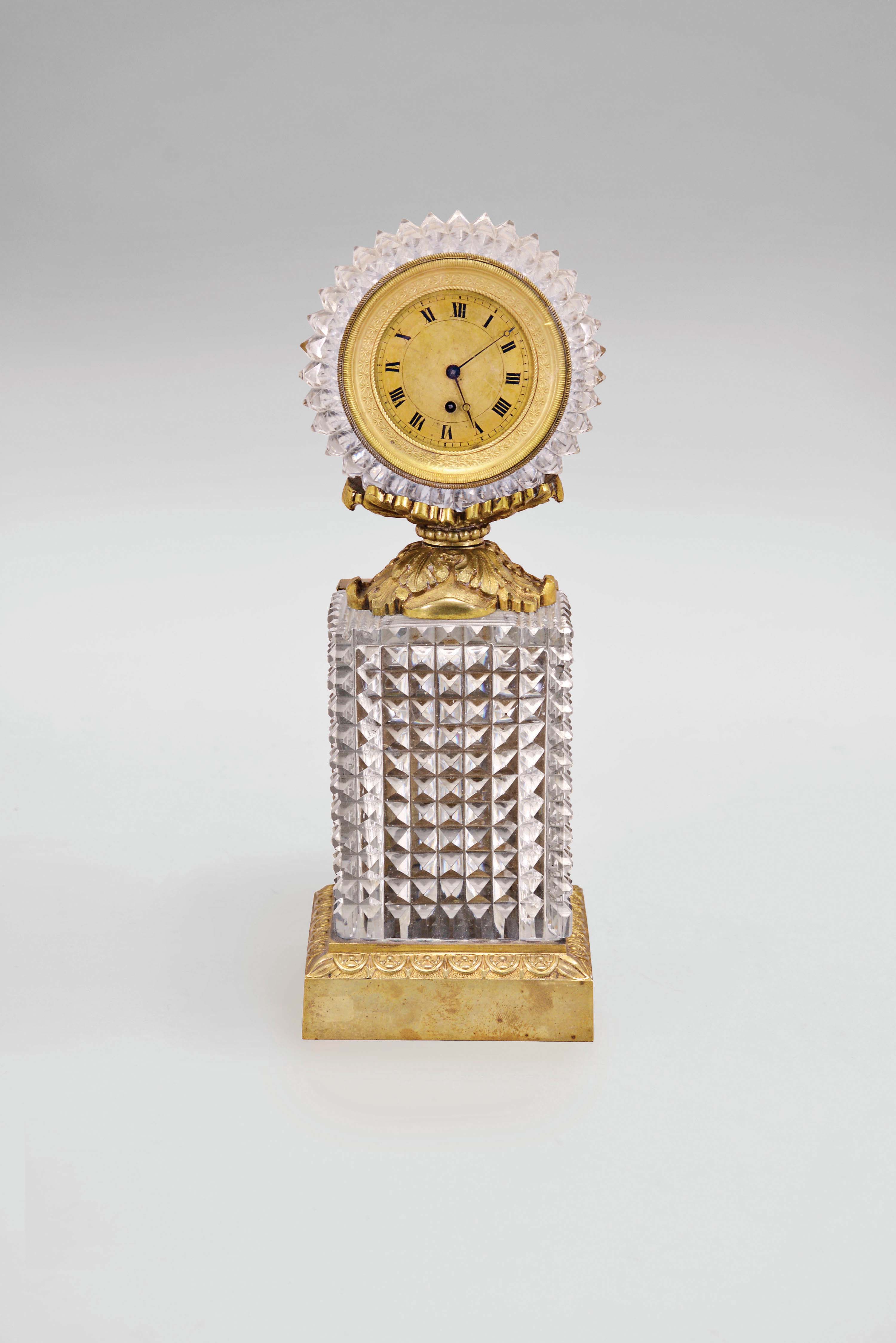 France, a gilt bronze and cut glass desk timepiece, egg and dart molded plinth with rectangular, diamond pattern, cut, colorless glass pedestal, supporting a gilt, acanthus ornamented cradle, holding the round, diamond cut timepiece case, gilt bezel, roman numeral gilt dial with blued steel Breguet style hands, and 30 hour, full plate verge fusee watch movement signed Thomas Langlois, a Paris — Antique Clocks Price Guide