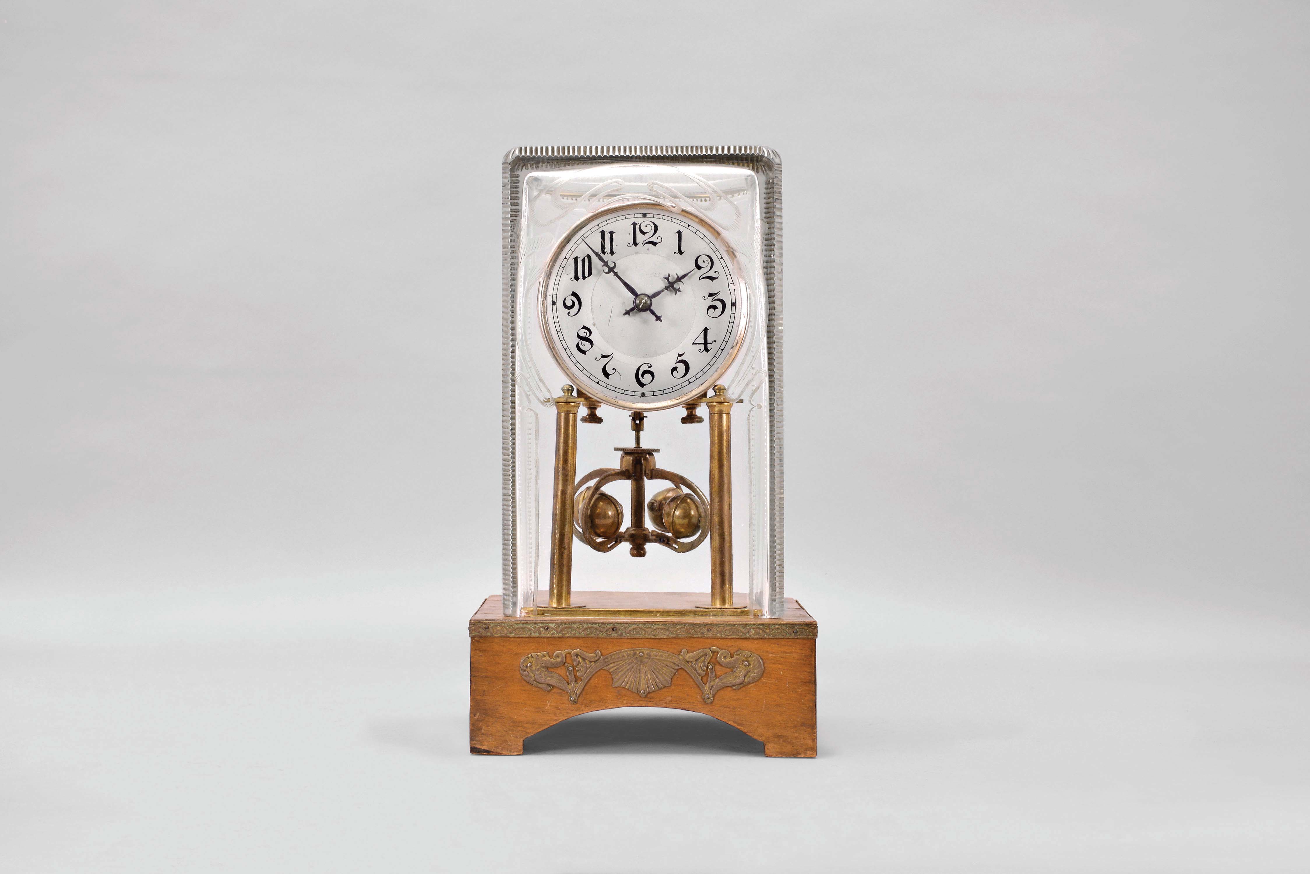 Jahresuhrenfabrik, Germany, an unusual year going mantel clock with torsion pendulum, wooden base with applied brass ornament, with conforming, rectangular, cut glass dome containing the 400 day timepiece with deadbeat escapement, Arabic numeral silvered dial, blued steel hands, and unusual four ball pendulum — Antique Clocks Price Guide