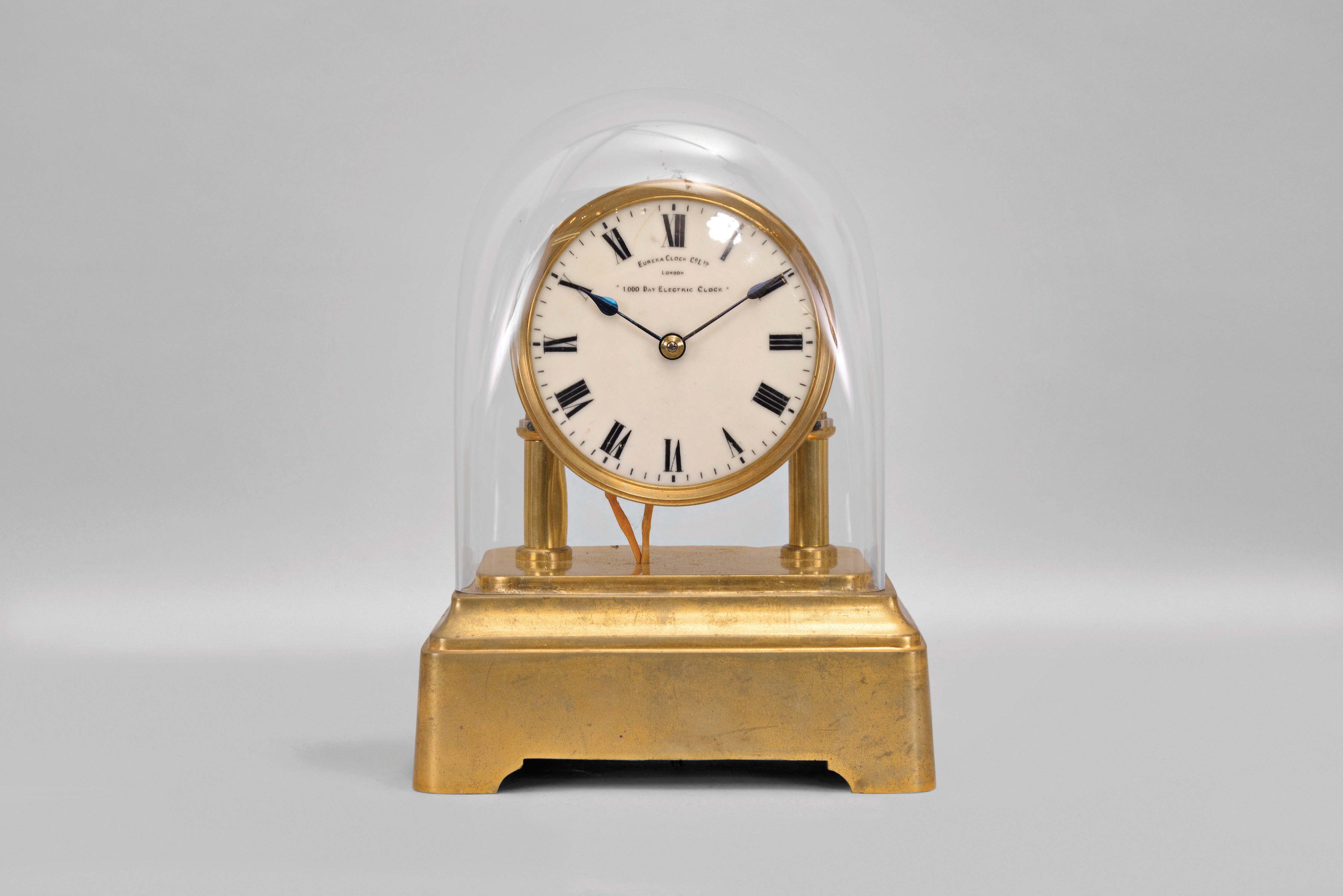 Eureka Clock Co., London, battery powered mantel clock with oversized balance wheel movement on a brass base and a cream color porcelain dial, s#2550 — Antique Clocks Price Guide