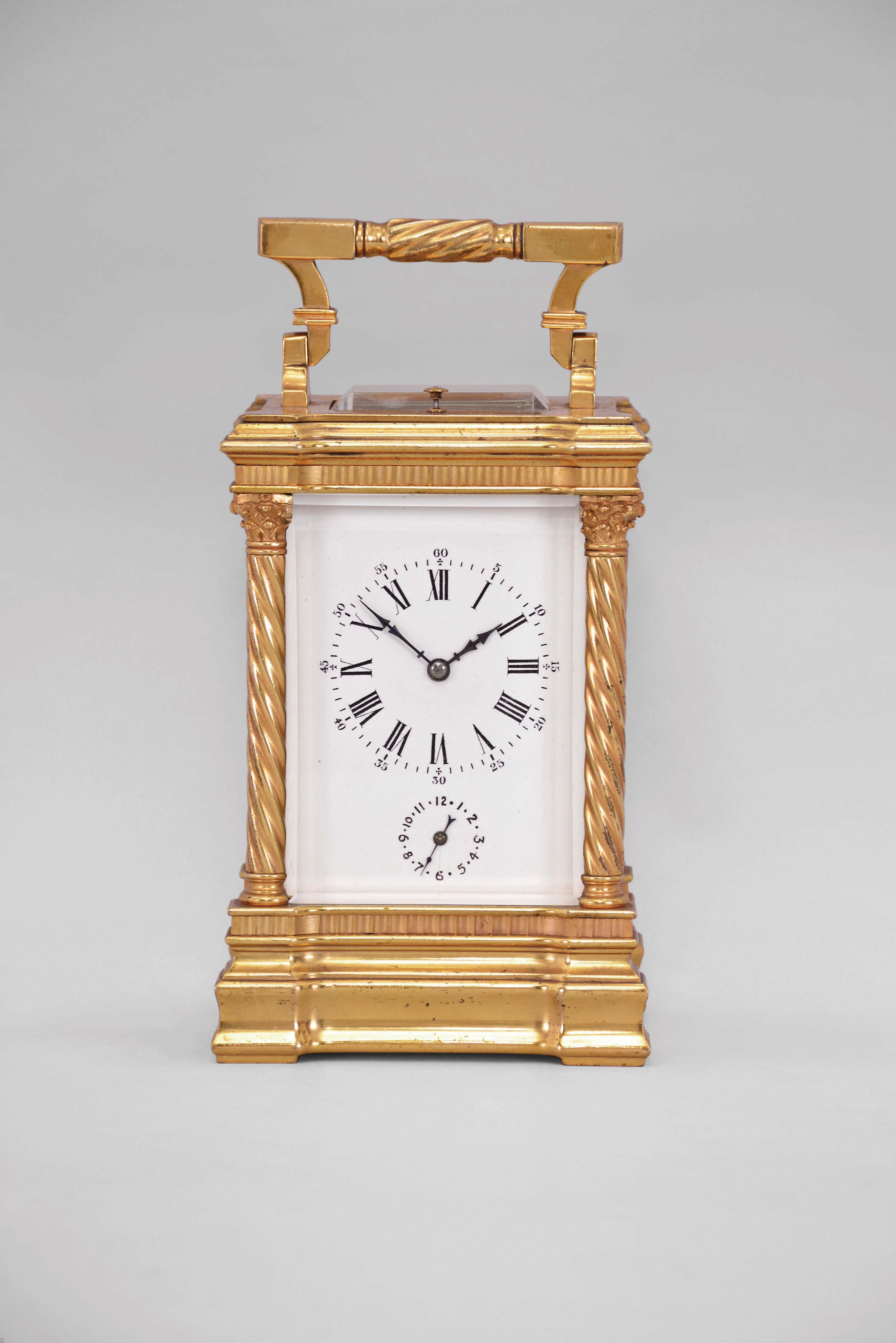 France, a good hour repeating, Anglaise Riche variant carriage clock with alarm, the gilt case with molded base and fluted band supporting twisted columns with Corinthian capitals, the entablature with fluted band, and stepped, molded cornice, case top with folding handle, roman numeral white enamel dial, blued steel distaff hands, three train movement with lever platform, sounding the hour and half hour in passing, and repeating the last hour on demand — Antique Clocks Price Guide
