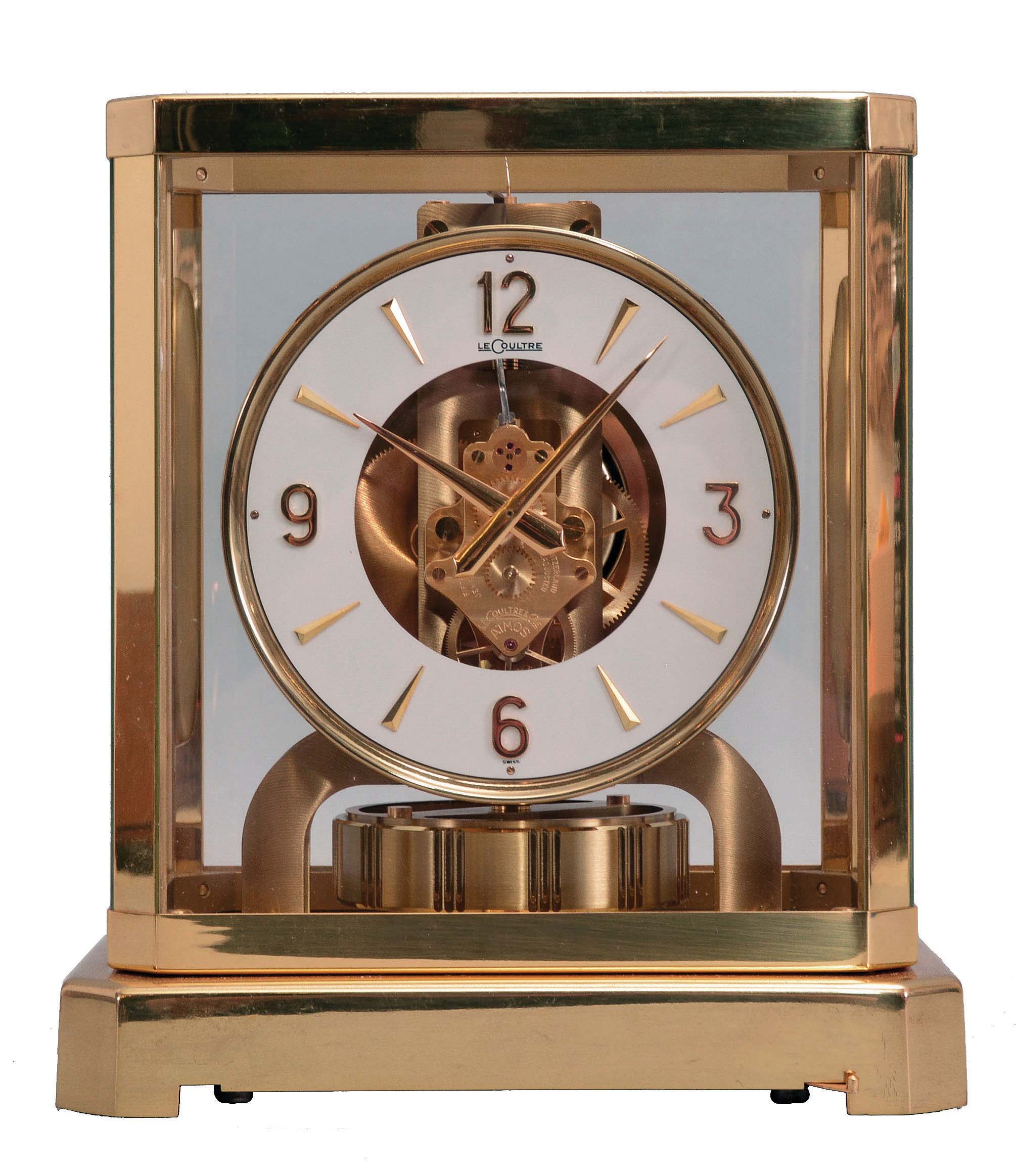 Jaeger- LeCoultre, Switzerland, "Atmos" clock, 15 jewel movement, gilt torsion pendulum, round white painted dial with applied gilt Arabic numerals and arrow markers, gilt hands, serial #212518, c1979. — Antique Clocks Price Guide