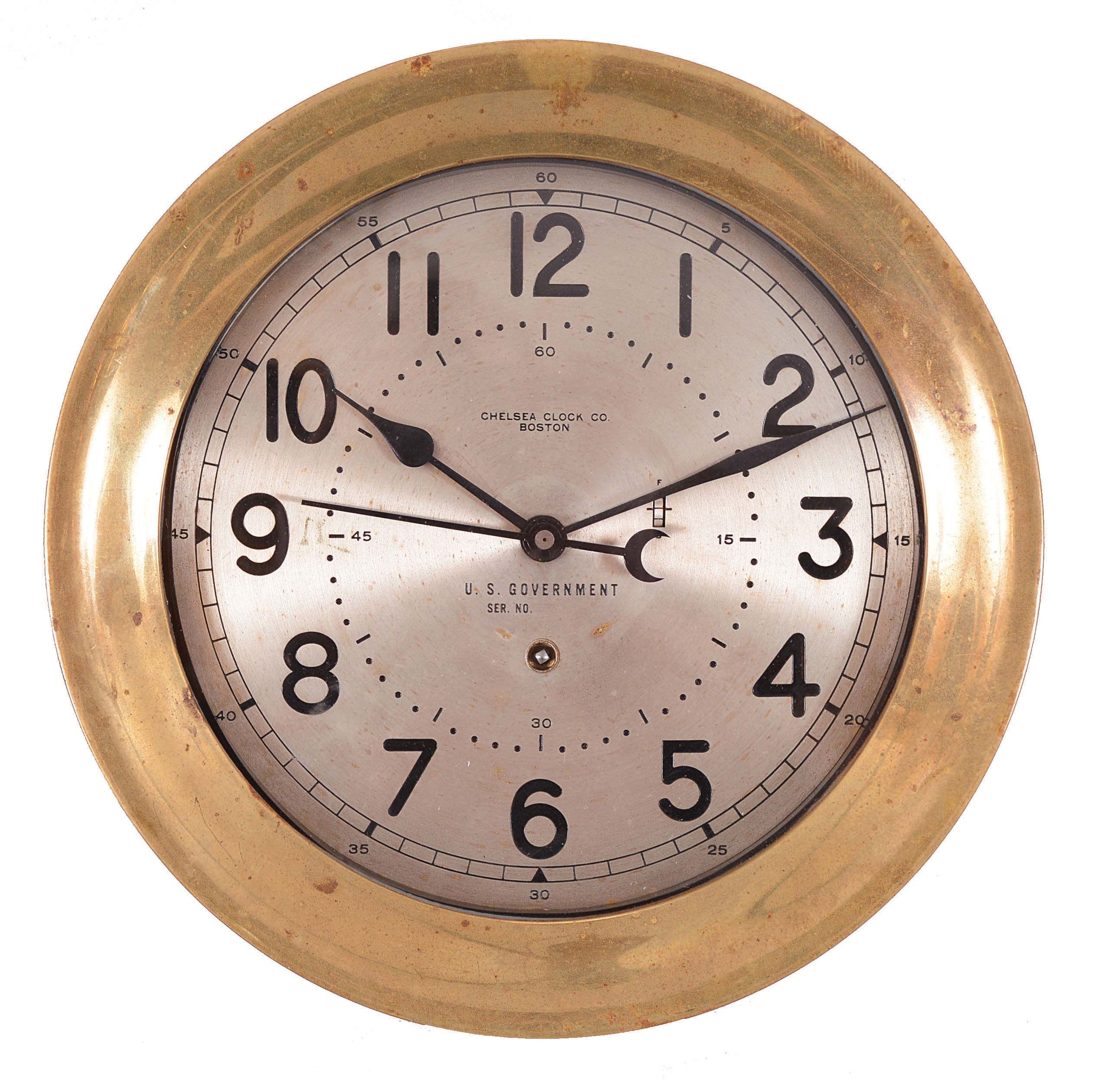 Chelsea Clock Co., Boston, Mass., "12E Deck &amp; Engine Room Clock", 8 day, time only, spring driven movement with jeweled lever escapement and center seconds in a brass case with hinged bezel, 8.5 inch silvered dial signed by the maker and "U.S. Government" with black Arabic numerals, movement serial number 599362, c1954. — Antique Clocks Price Guide