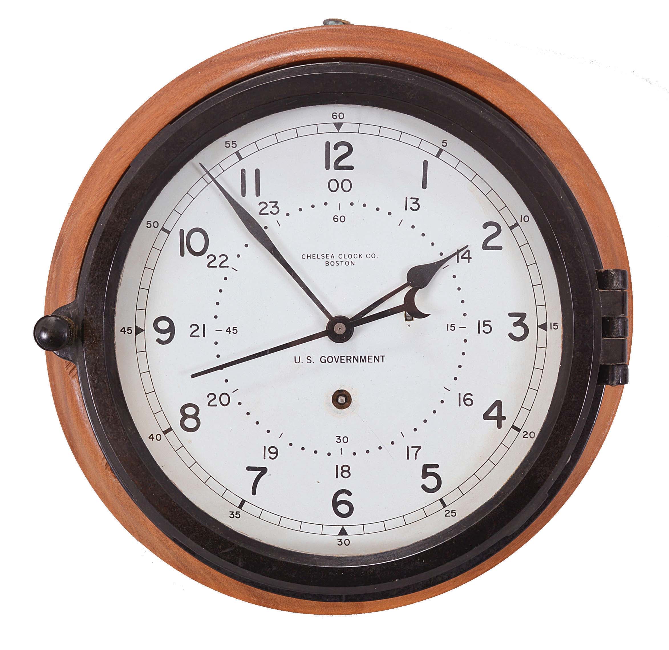 Chelsea Clock Co., Boston, Mass., "12E Deck &amp; Engine Room Clock", 8 day, time only, spring driven movement with jeweled lever escapement and center seconds in a black phenolic case with hinged bezel, 8.5 inch white dial signed "U.S. Government" with 12 and 24 hour markers, blued steel spade hands, all mounted to a molded hardwood backer, movement serial number 871004, c1992. — Antique Clocks Price Guide