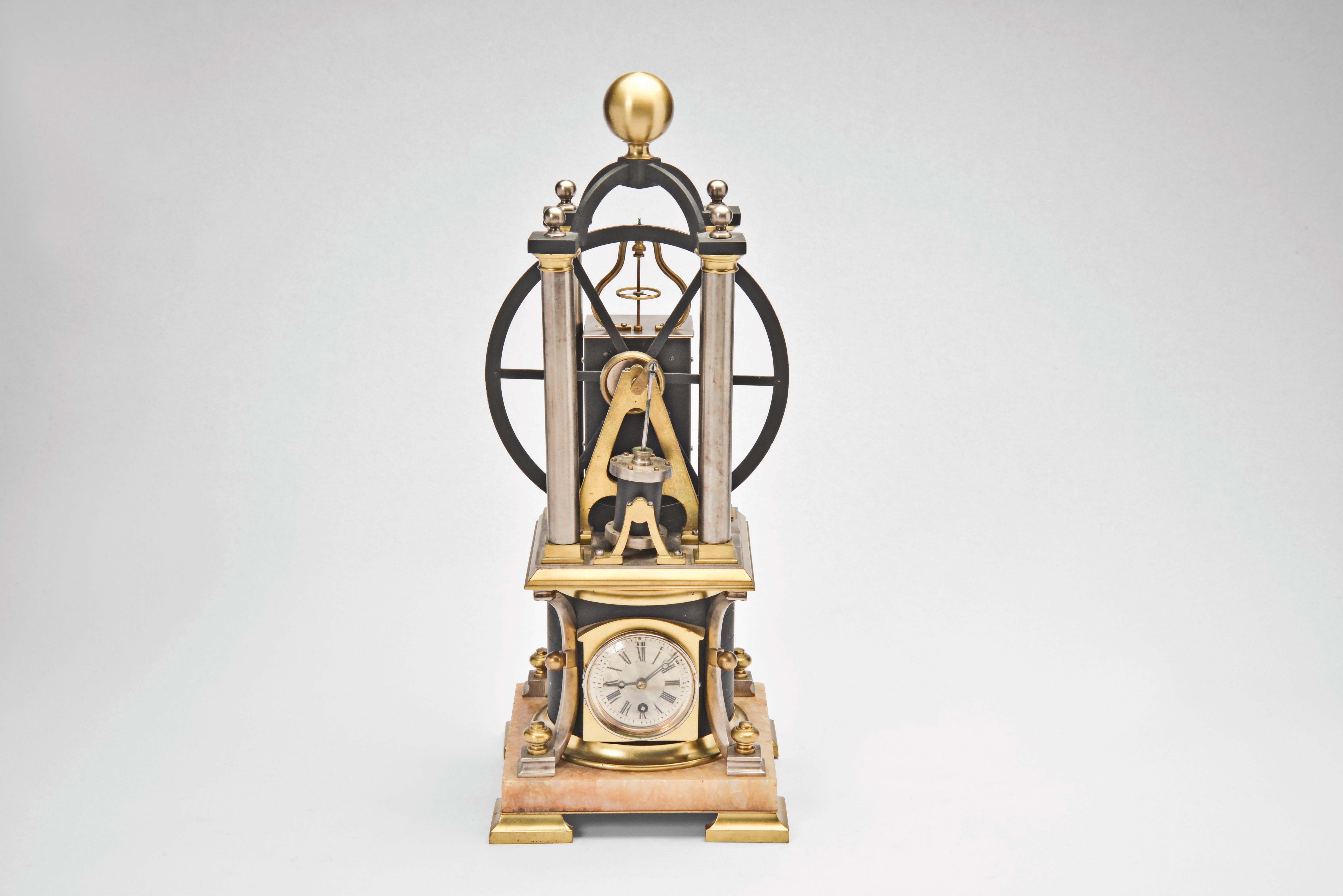 France, possibly Andre Romain Guilmet, a rare, automated, oscillating cylinder steam engine timepiece, the honey onyx square base on gilt feet, and supporting the black bronze boiler with cove molded top and bottom, below the engine itself, comprised of a large, A frame supported, spoked flywheel, connected to a rocking cylinder through a cranked linkage, the movement powering the automation contained in a black enclosure behind the engine, the enclosure top with a rotating governor in a bell shaped frame behind the wheel, surrounded by four silvered columns, and surmounted by an X shaped, arched frame with central spherical finial, the 11 jewel lever platform movement with Roman numeral silvered dial and blued steel Breguet style hands — Antique Clocks Price Guide