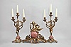 France, three piece mantel garniture set, 8 day, time and strike, spring driven pendule de Paris movement, the case with cast Rococo style base supporting a sphere with applied roman numerals, the hands in the form of a snake, all surmounted by a cast metal putto with outstretched wings holding a garland, the two matching side pieces with putti holding aloft the candleabra.