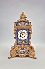 Grohe, a Paris, an ornate, renaissance revival, gilt bronze and porcelain mounted mantel clock, the case resting on gryphon and scroll feet, with dome top and fruit filled urn finial, and replete with rococo and renaissance revival ornament, the panels in the manner of Jacob Petit, with blue ground, and gilt bordered, floral vignettes, the front with a shepherdess in a landscape playing a flute below the roman numeral dial with floral wreath, fancy gilt hands, 8 day, two train pendule de Paris movement striking on a bell