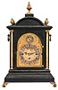 England, for Theodore B. Starr, New York, ebonized, quarter striking bracket clock, the molded base with gilt scroll feet, gilt, fluted columns supporting the cornice and dome top, and flanking the cast, foliate bezel and composite dial with Roman numeral chapter ring and strike selector in the arch, sides with pierced frets and carrying handles, top with five pineapple finials, three train fusee movement chiming on eight bells, and striking the hours on a gong