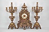 Jules-Edouard Dehon, Switzerland for Tiffany & Co., New York, three piece mantel garniture set, 8 day, time and strike, spring driven movement in a elaborately sculpted cast brass Renaissance revival case featuring claw feet, foliate heads, floral motifs, peripheral fretwork, and lion masks in profile, cream porcelain dial with blued steel hands, all topped by a large urn finial. Two matching brass candelabra holding six candles each.