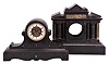 Clocks- 2 (Two) French Black Mantel: (1) H.P. & Co., Paris, black mantel clock, 8 day, time and bell strike, spring driven pendule de Paris movement with exposed Brocot escapement in a black slate tambour-form case with incised floral patterns and green malachite accents, white enamel dial ring with Roman numerals, and black Roman style steel hands, c1900. (2) France, clock case only, black slate architectural case with stepped, molded base, two sets of three fluted columns flanking the central opening for the dial, pediment with incised designs and low relief frieze depicting Alexander the Great making his triumphal return to Babylon, c1890.