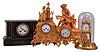 Clocks- 4 (Four) European shelf: (1) Gustav Becker, German, 400 day or anniversary clock, spring driven movement with a solid disk torsion pendulum, c1915. (2) Japy Freres, Paris, mantel clock, 8 day, time and strike, spring driven movement with silk thread suspension in an ormolu case featuring a woman in prayer, c1855. (3) Japy Freres, Paris, mantel clock, 8 day, time and strike, pendule de Paris movement in an ormolu case depicting a fisherman, c1875. (4) France, mantel clock, 8 day, time and strike, spring driven pendule de Paris movement in a black slate case with variegated marble accents, c1880.