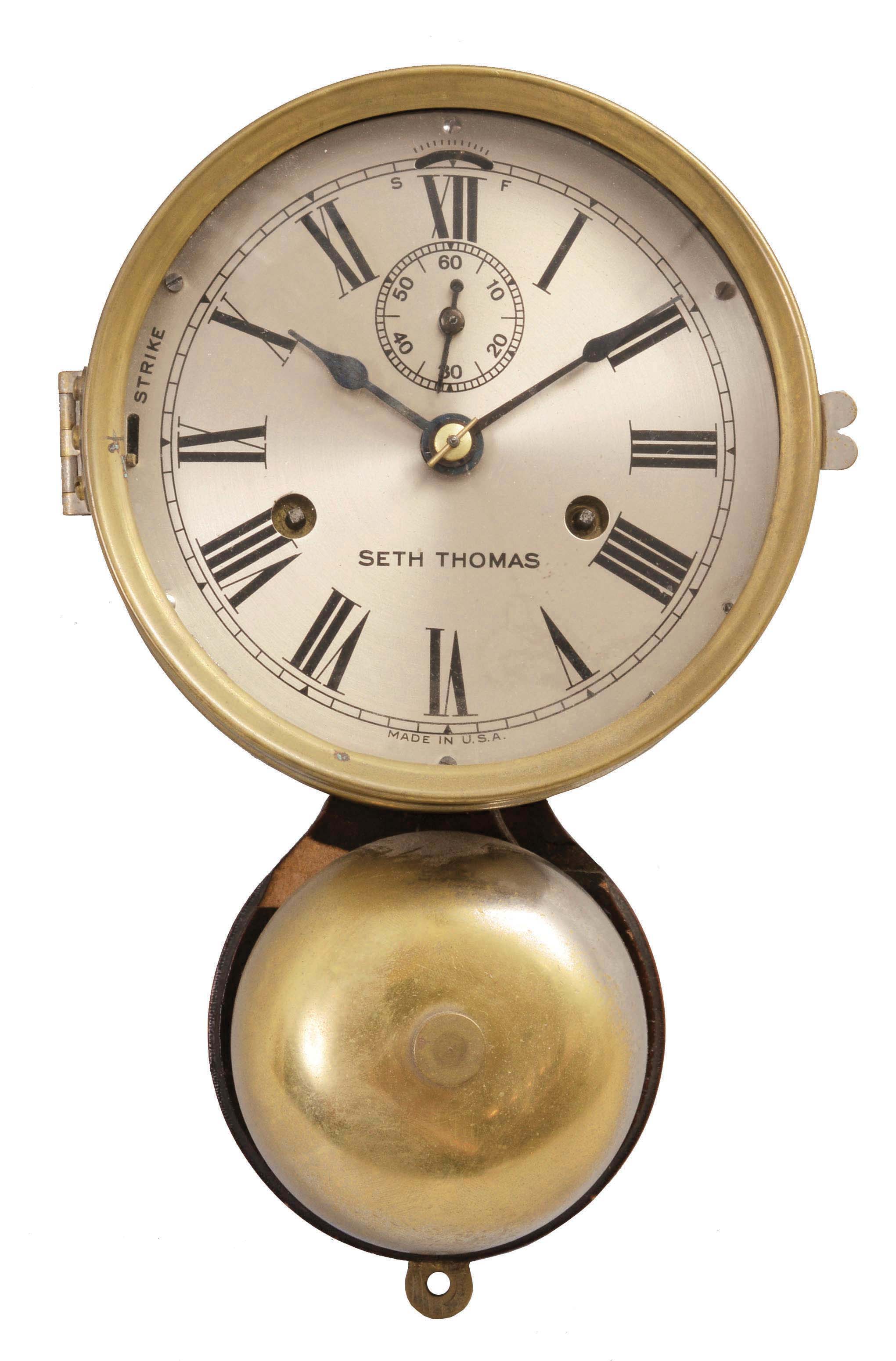 Seth Thomas Clock Co., Thomaston, Conn., "Ship's Bell" clock, 30 hour, time and ship's bell strike, spring driven, balance wheel movement in a brass case with outside bell, silvered dial, and blued steel hands, all mounted to a wood backboard. — Antique Clocks Price Guide