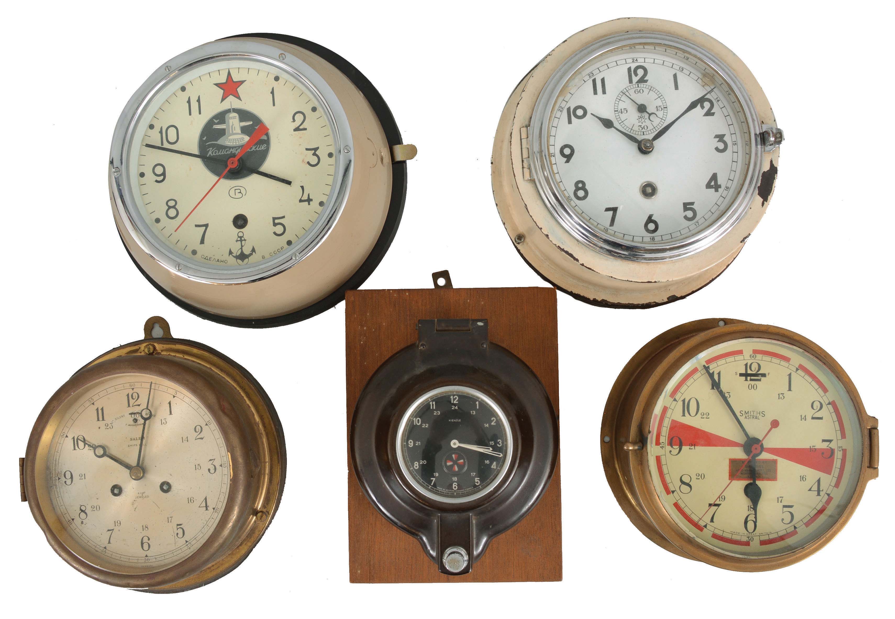 Clocks- 5 (Five) English, German, and Russian Marine Clocks: (1) Smiths Astral radio room ship's clock in a brass case; (2) Junghans ship's clock in a white metal case; (3) Salem time and ship's bells with German movement in a brass case; (4) Kienzle sealed clock, probably for maritime use; (5) Russian submarine clock with mounting board. — Antique Clocks Price Guide