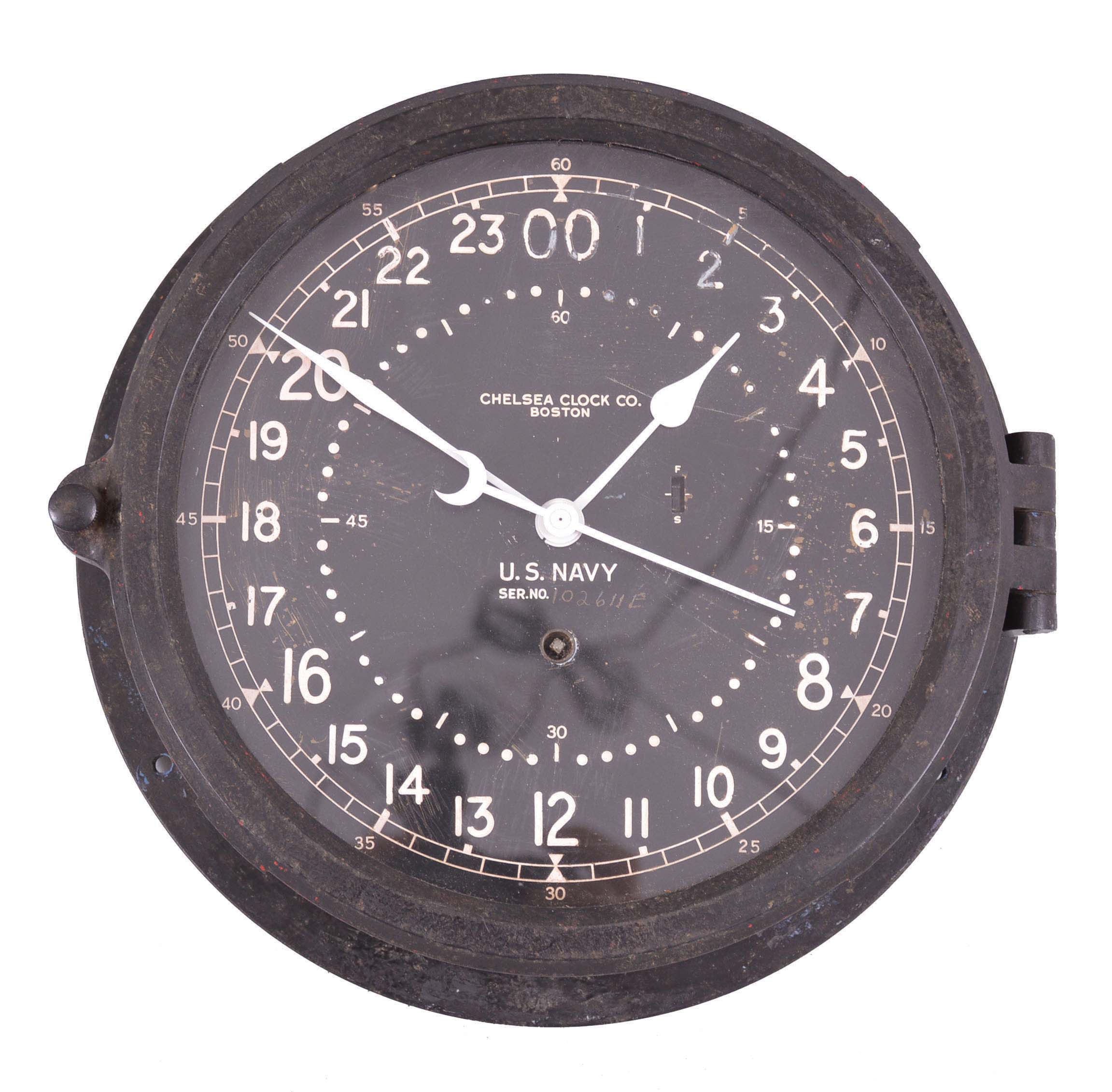 Clock- 2 (Two) Boston and Chelsea: (1) Boston Clock Co., Boston for Tilden-Thurber, Providence, miniature timepiece, 8 day, time only, spring-driven balance wheel movement in a mahogany lancet top case with string inlay. (2) Chelsea Clock Co., Boston, for U.S. Navy, deck or engine room clock, 8 day, time only, spring-driven balance wheel movement in a black phenolic case with 8.5 inch 24 hour dial, serial number 418408, c1943. — Antique Clocks Price Guide