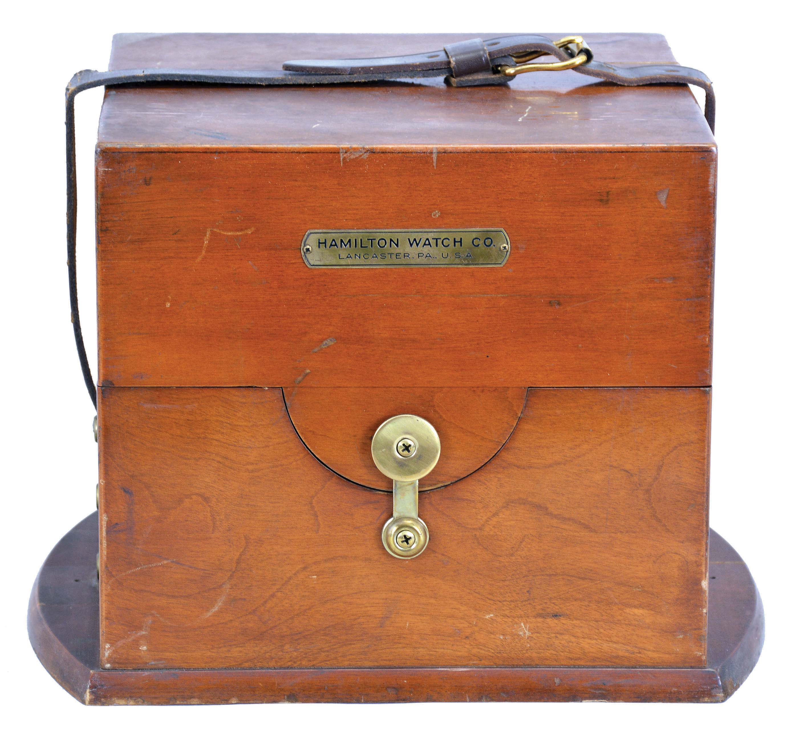Hamilton Watch Co., Lancaster, Penn., model 21 marine Chronometer, 14 jewel, key wind and set fusee movement with grained nickel plates, spring detent escapement, large monometallic balance and helical balance spring, Arabic numeral metal dial with wind indicator, black painted steel spade and poker hands, with gimbaled brass bowl, contained in a three tier mahogany box with brass furniture and padded mahogany outer box with leather strap, serial #2E12959 — Antique Clocks Price Guide