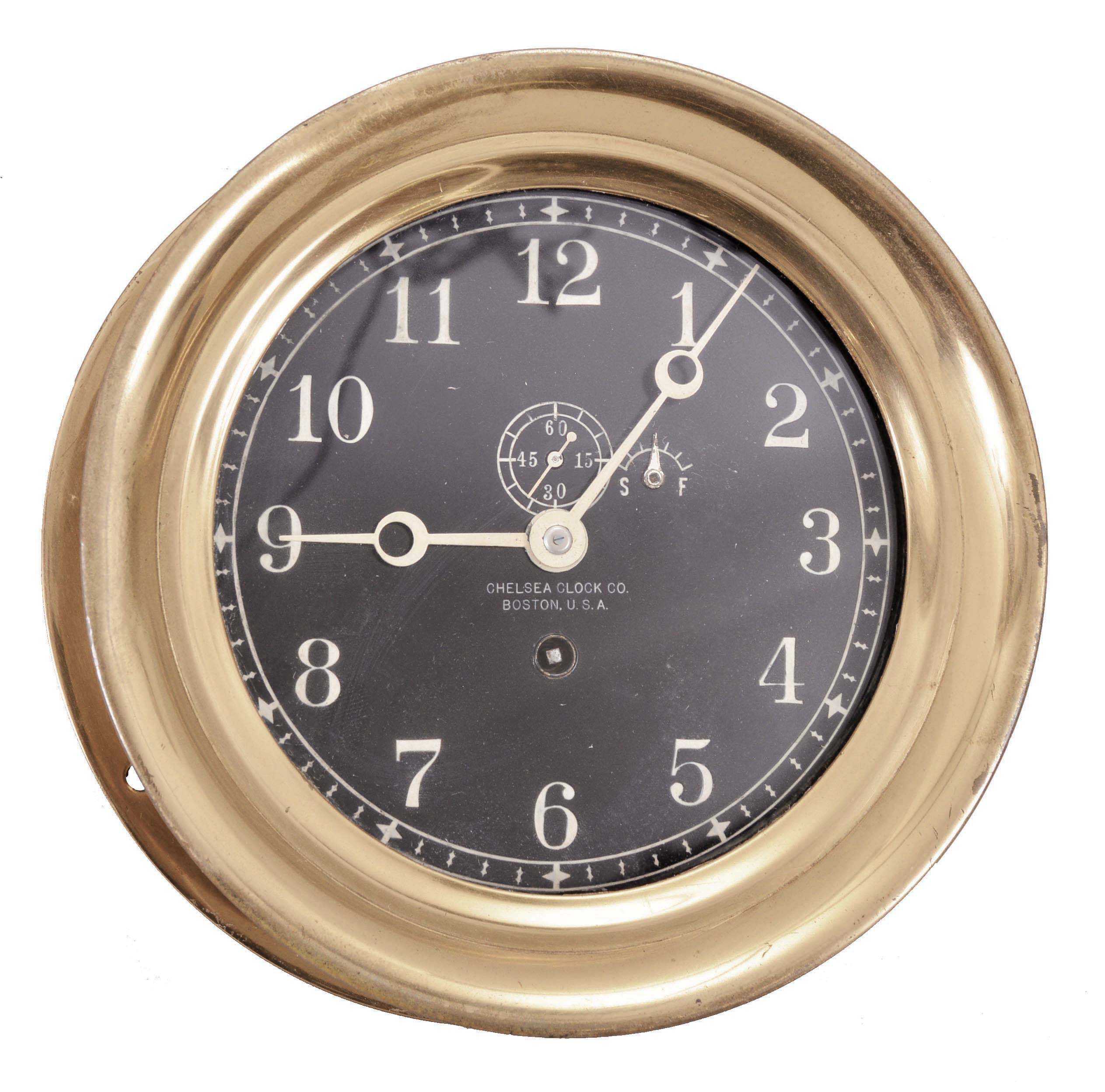 Chelsea Clock Co., Boston, Mass., deck clock, 8 day, time only, spring-driven jeweled balance wheel movement in a brass case with hinged bezel, 6 inch black dial with white Arabic numerals, subsidiary seconds, and Breguet style hands. — Antique Clocks Price Guide