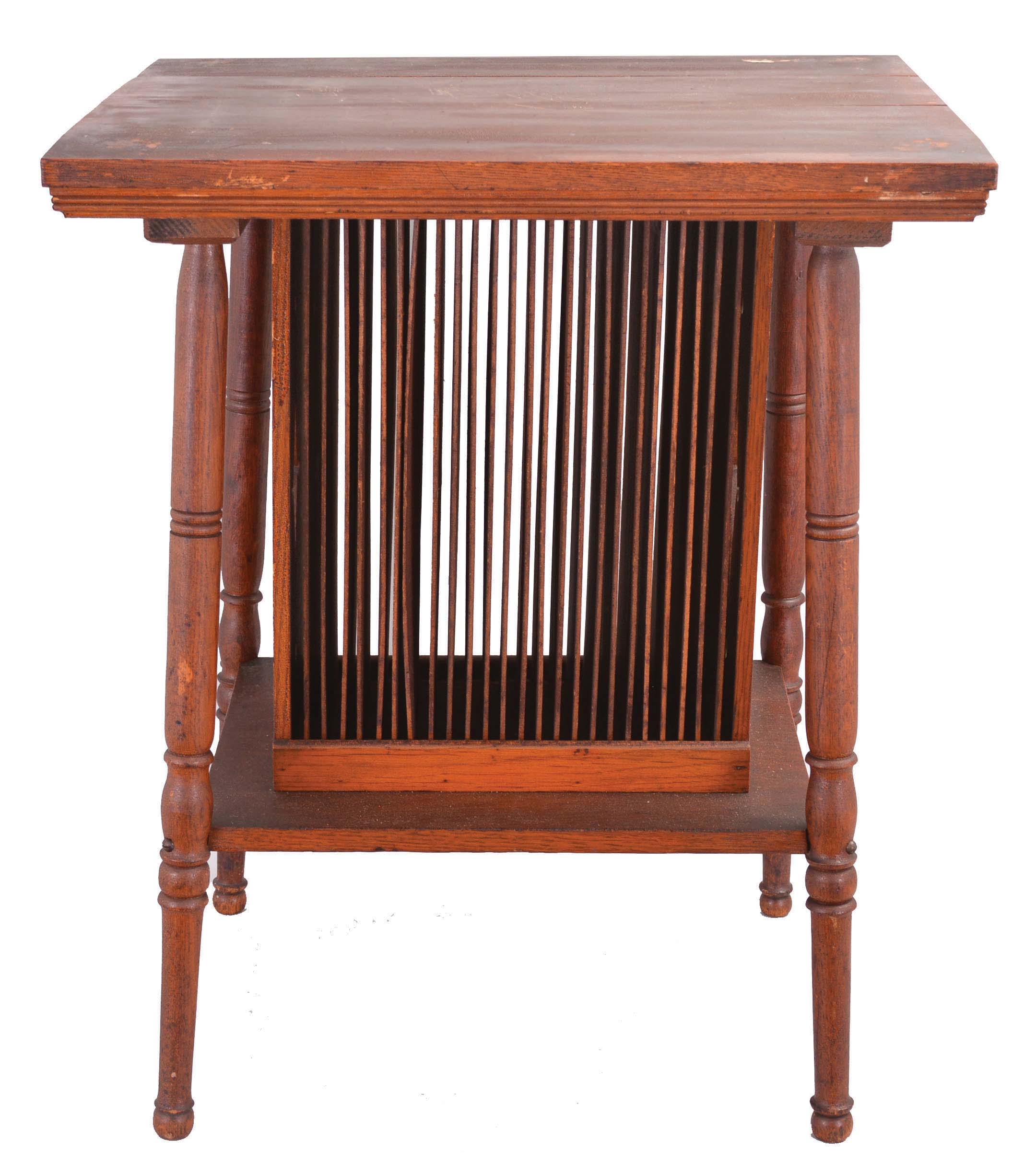 Regina music box stand in oak with turned legs, center section holding a series of vertical slats for music box disc storage, table top with beaded edge. — Antique Clocks Price Guide