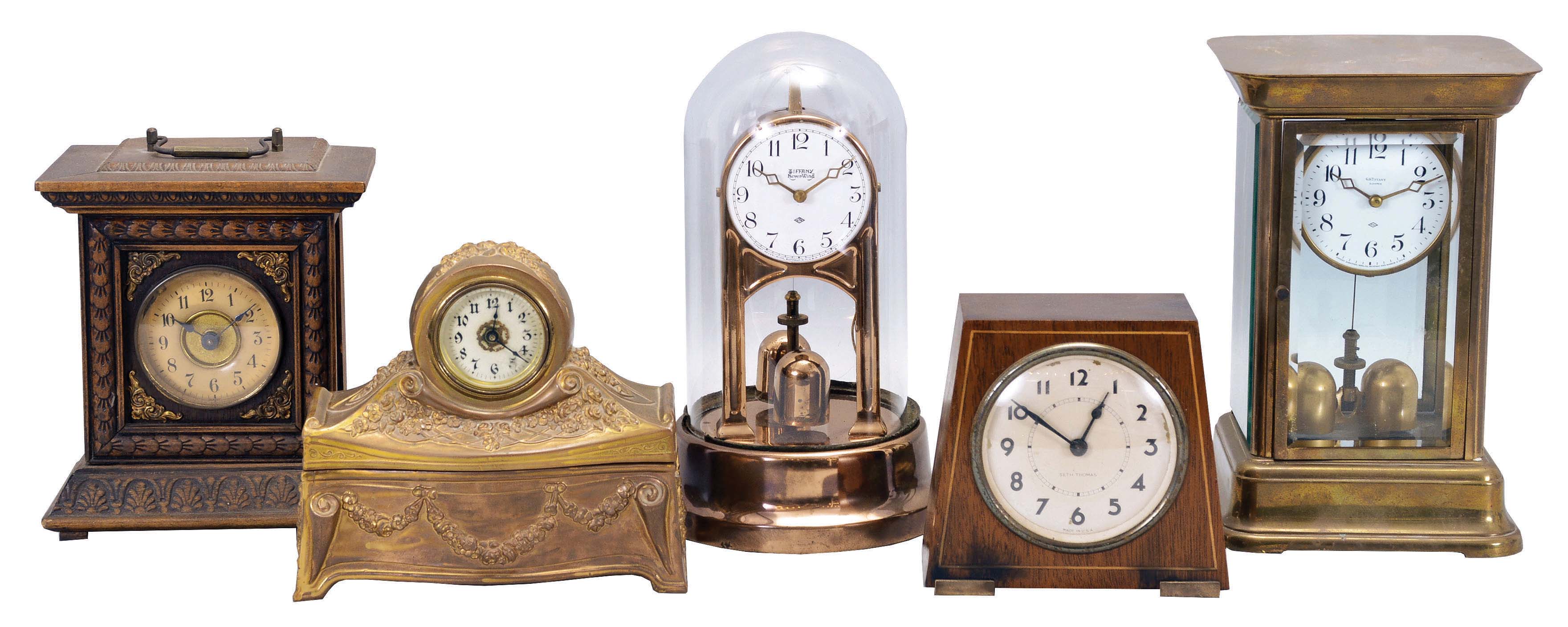 Clocks- 5 (Five) Desk: (1) Junghans, Germany, alarm clock, 30 hour, time and alarm, spring driven movement in a molded wood case; (2) Seth Thomas, Conn., desk clock, 30 hour, spring driven movement in a mahogany case with banding; (3) Connecticut, bedside clock, 30 hour, spring driven movement in a cast metal case with jewelry tray; (4) and (5) Tiffany electromechanical clocks with torsion pendulums in metal and glass cases. — Antique Clocks Price Guide