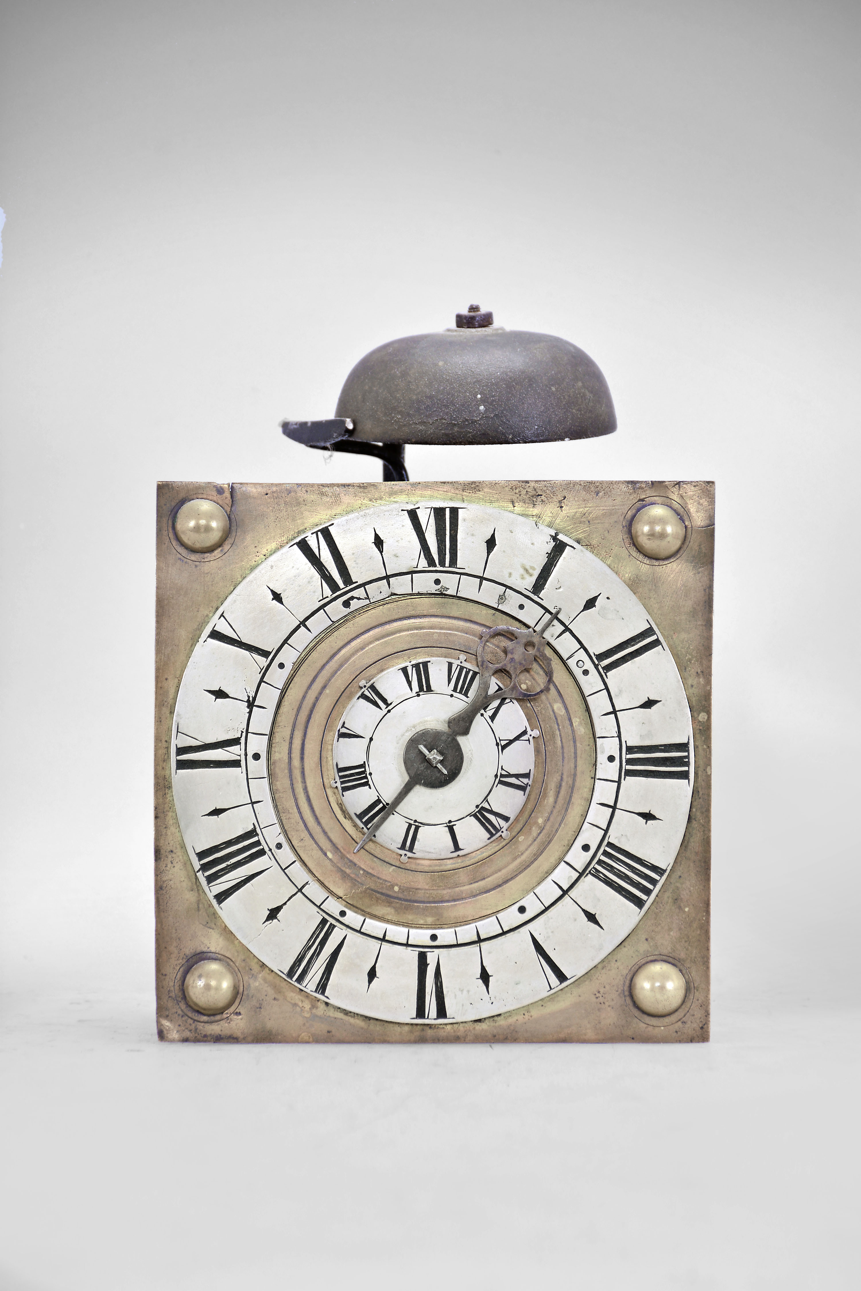 England, a small, 18th century 30 hour hanging alarm timepiece, square brass dial plate decorated with hemispheres at the corners, silvered roman numeral chapter ring and alarm disc, single blued steel hand, iron square posted movement with recoil escapement and seconds pendulum, the back with loop and spikes for hanging, and lead weights — Antique Clocks Price Guide