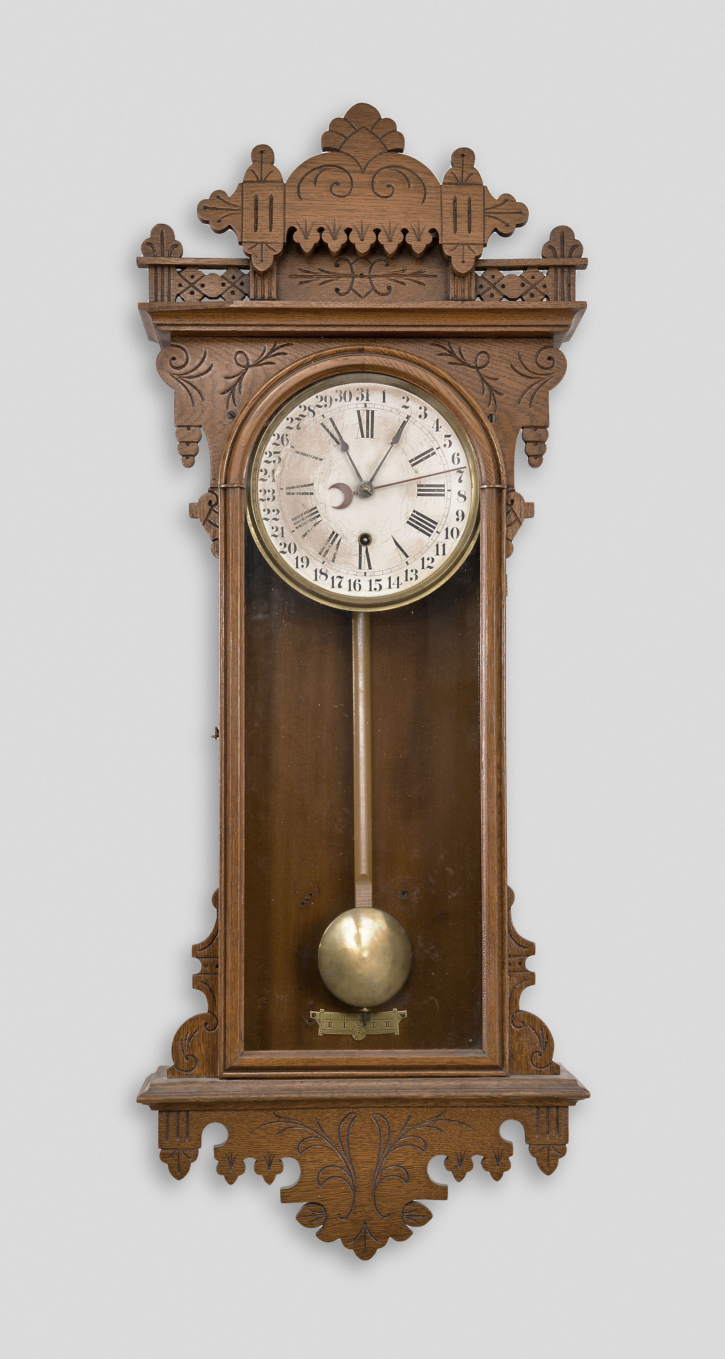 Ansonia Clock Co., New York, for Metropolitan Manufacturing Co., "Eclipse" hanging gingerbread clock, 8 day, time and simple calendar, spring driven movement in an oak case. — Antique Clocks Price Guide