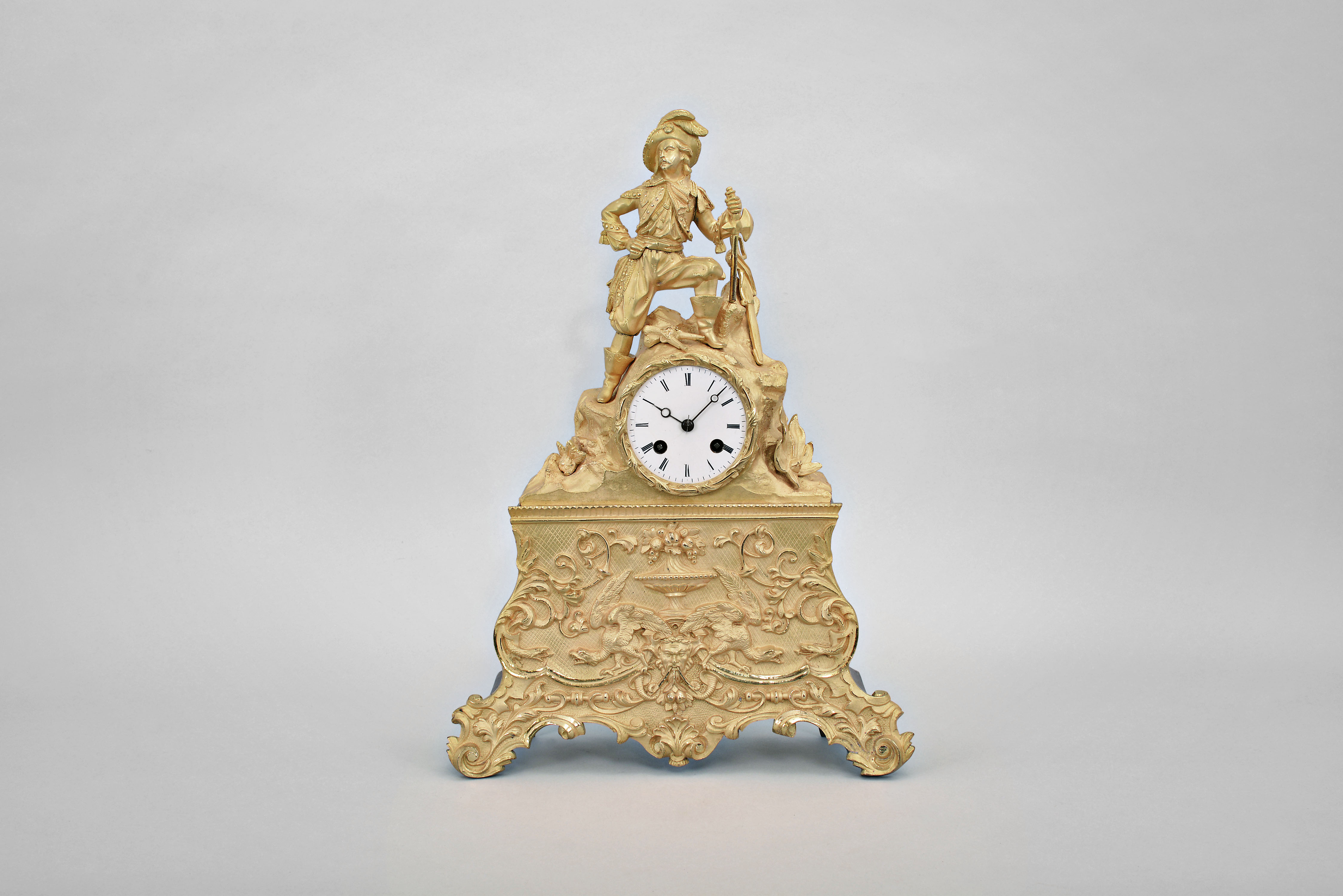 Japy Freres &amp; Cie, Paris, figural mantel clock, 8 day, time and strike, spring driven pendule de Paris movement in an elaborate gilt metal case surmounted by a warrior leaning on an ax, a saber behind him, and a brace of pistols between his feet, 3 inch white enamel dial, and blued steel Breguet style hands. — Antique Clocks Price Guide
