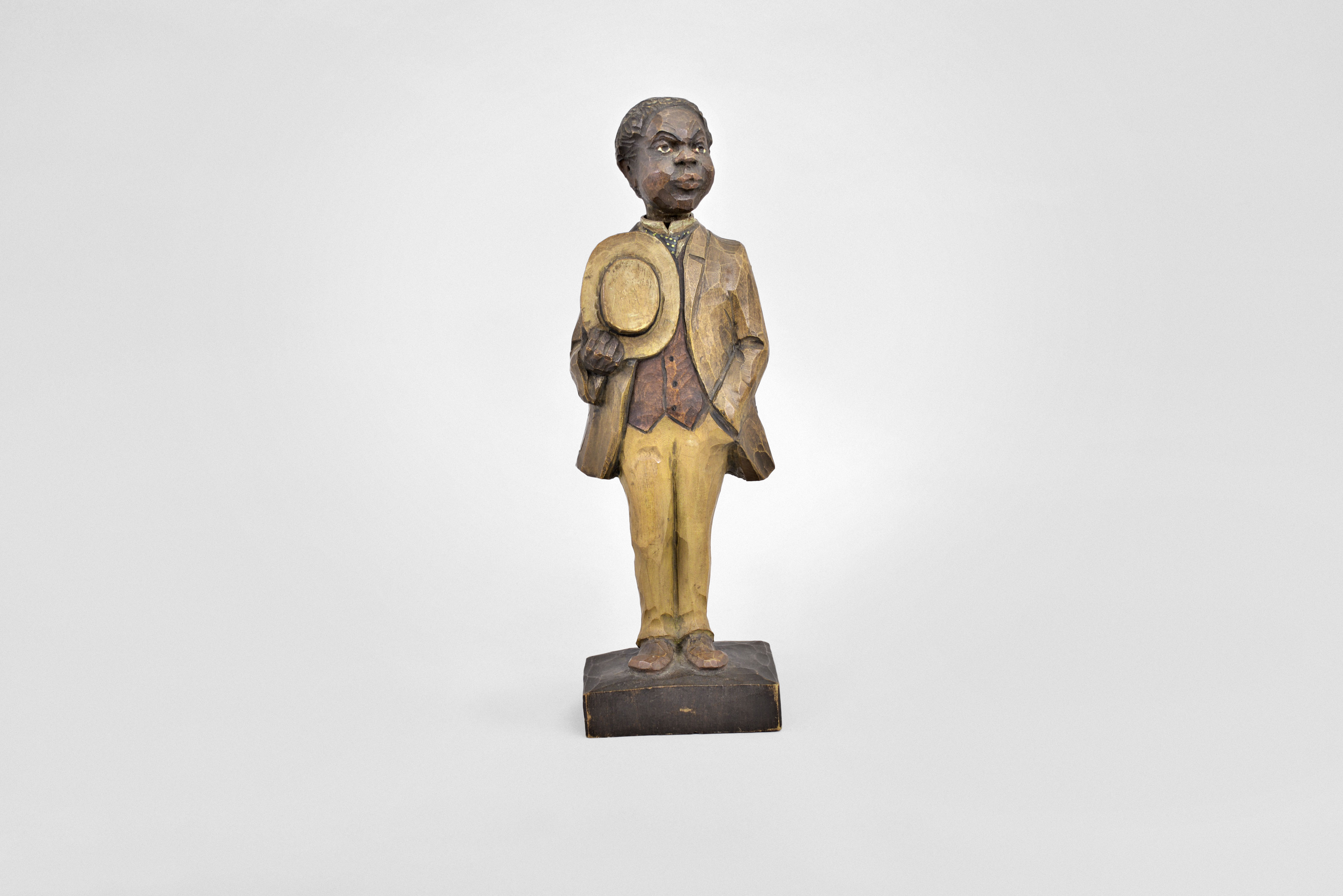 Karl Griesbaum, Triberg, Germany, gentleman whistling figure, spring driven brass movement powering air bellows, slide whistle, and turning head motion, hidden within a hand carved wooden figure depicting a black man in a light colored suit, straw hat in hand, whistling a tune. — Antique Clocks Price Guide