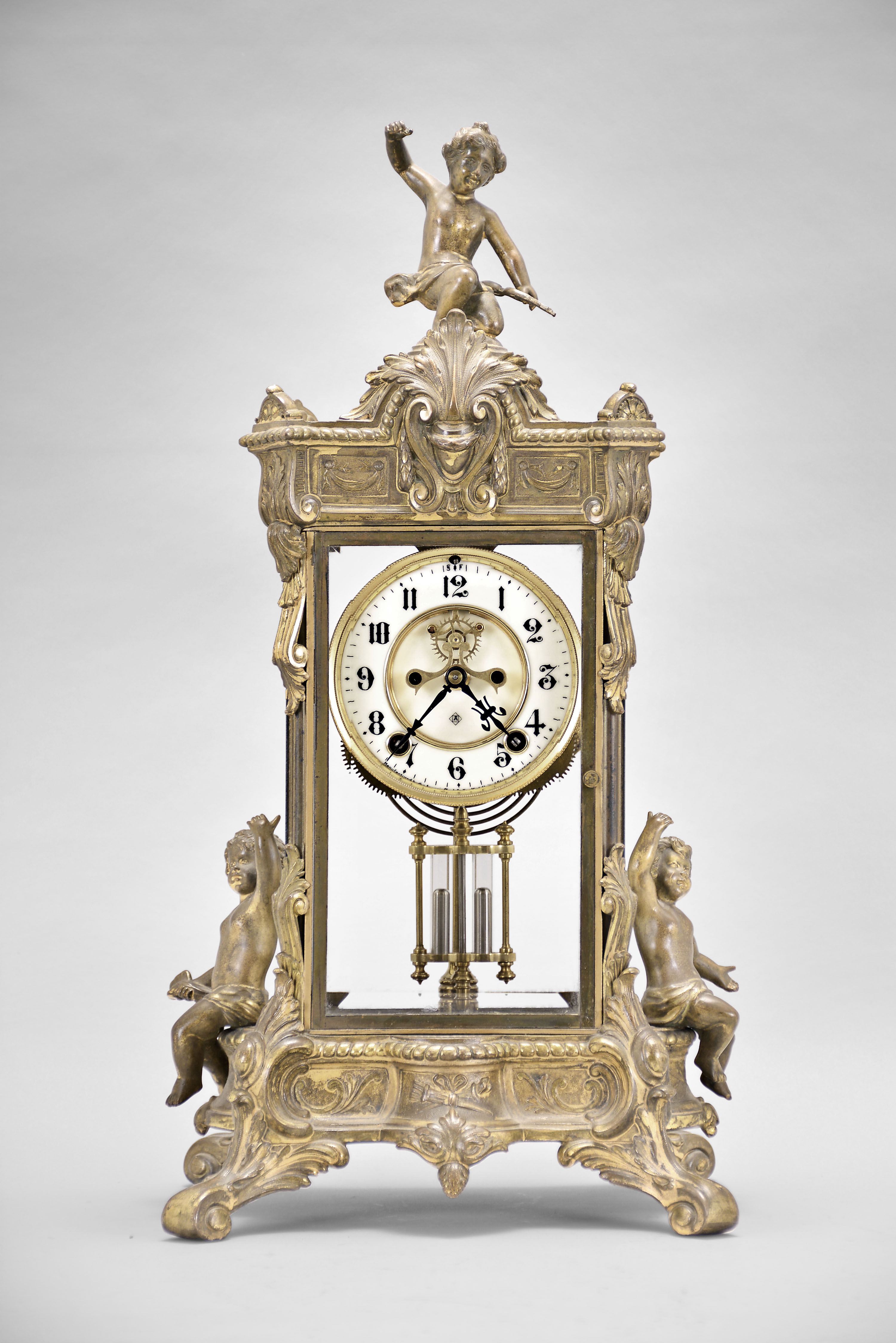 Ansonia Clock Co., New York, "Peerless" crystal regulator, 8 day, time and strike, spring driven movement with visible Brocot escapement in an ornate gilt metal case with two child figures on each side and Cupid with his bow on top, two piece enamel dial with blued steel hands and double-vial pendulum. — Antique Clocks Price Guide