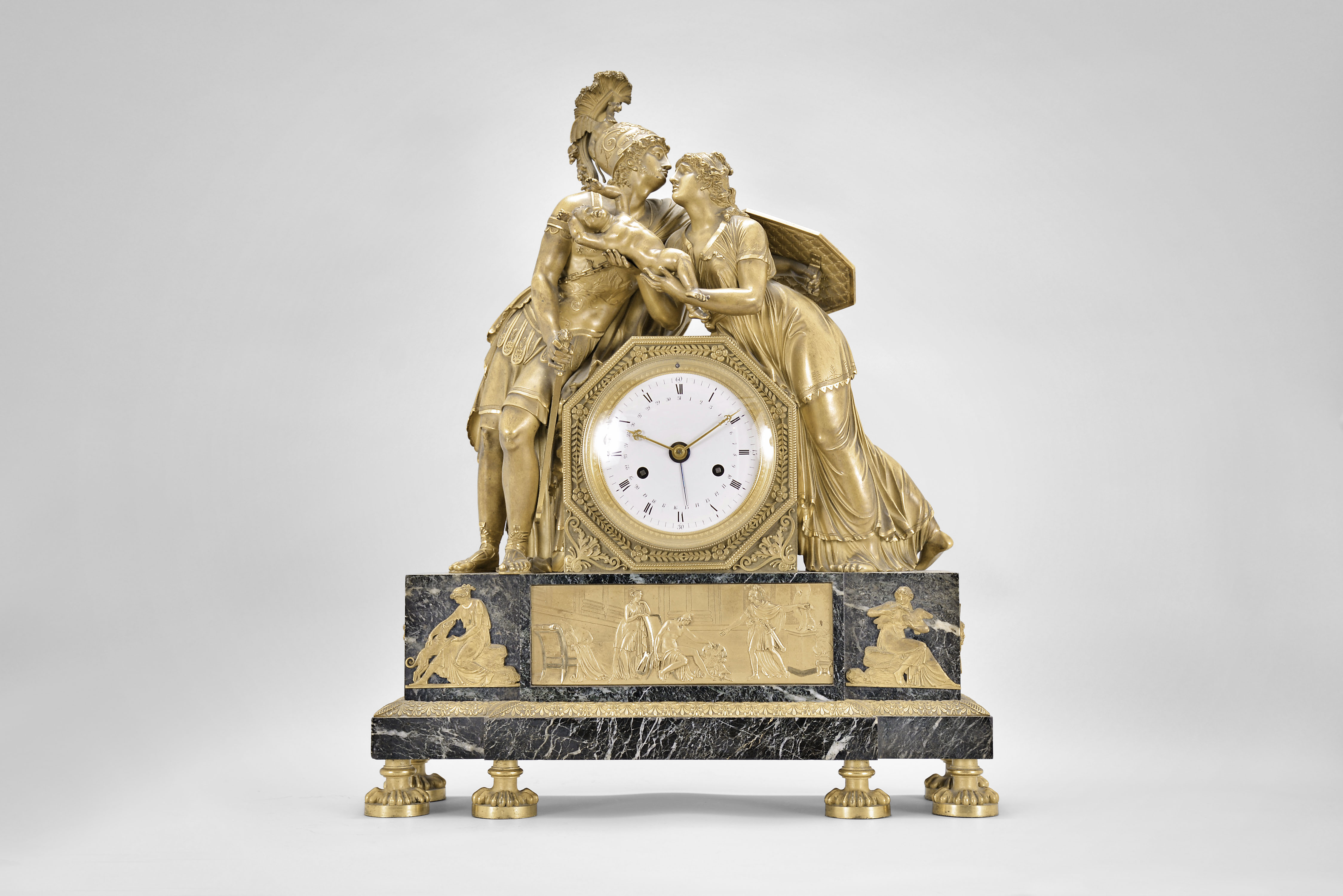 Attributed to Claude Galle, a monumental Verde Antico and gilt bronze mantel clock, "Hector's Farewell to Andromache", the stepped base resting on 6 four paw feet, palmette and bellflower ornamented base molding, the front with bas relief of Hector attempting to convince Paris to defend Troy, and with flanking mounts representing love and fidelity, and surmounted by figures of Hector and Andromache, Hector dressed for battle, and Andromache with a pained expression and holding their son Astyanax, the figures flanking the octagonal clock case containing a large, two train movement of 15 day duration, and with date function, roman numeral white enamel dial with inner date chapter, gilt and engraved brass hands with blued steel date indicator — Antique Clocks Price Guide