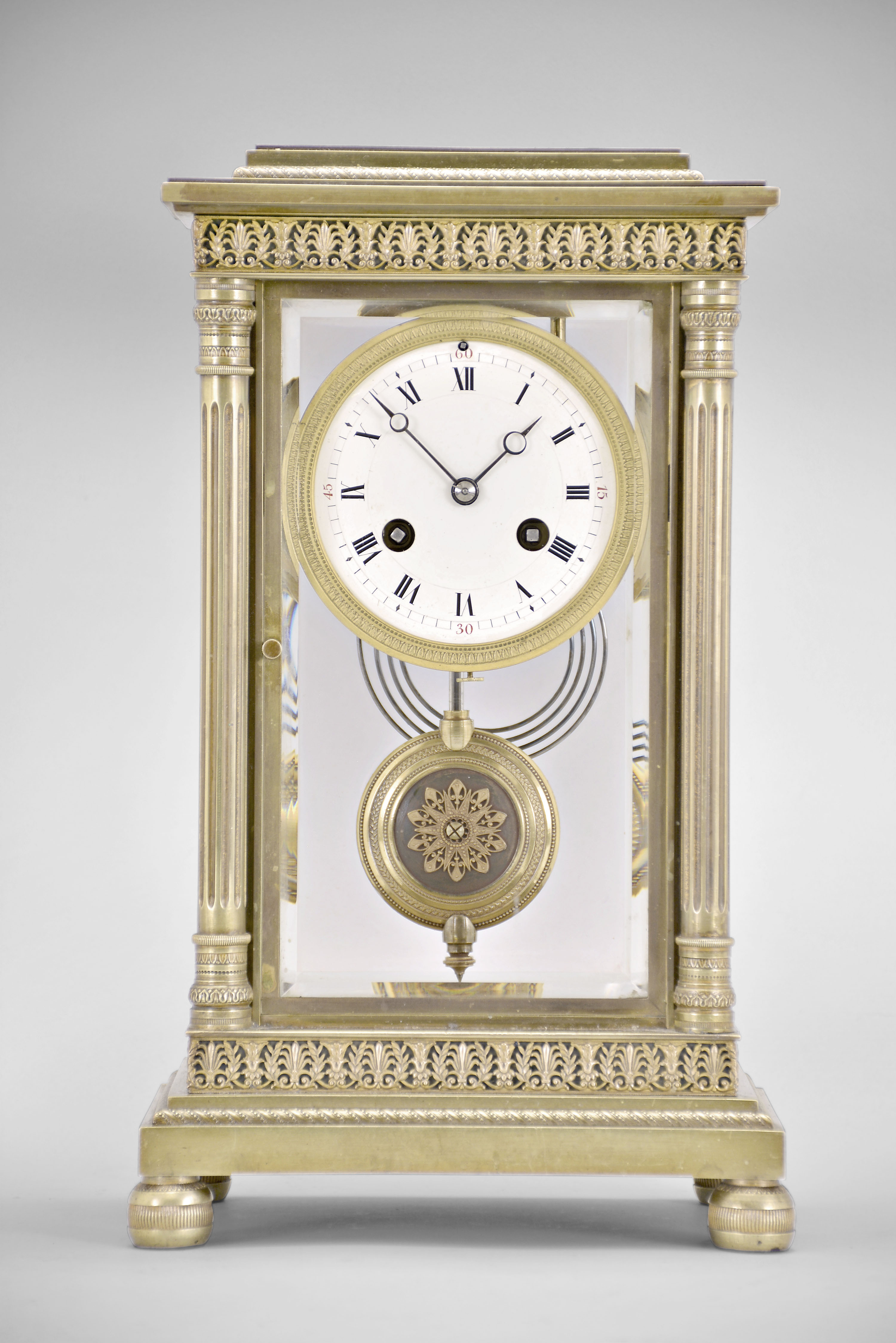Vincenti &amp; Cie, Paris, France, crystal regulator, 8 day, time and strike, spring driven pendule de Paris movement in a glazed brass case on cast bun feet supporting fluted columns on the front corners and pilasters on the back corners, stepped and molded base and top with repeating palmette and laurel fretwork, matching pendulum, Roman numeral white enamel dial with red Arabic numerals at the quarters, and blued steel Breguet style hands. — Antique Clocks Price Guide