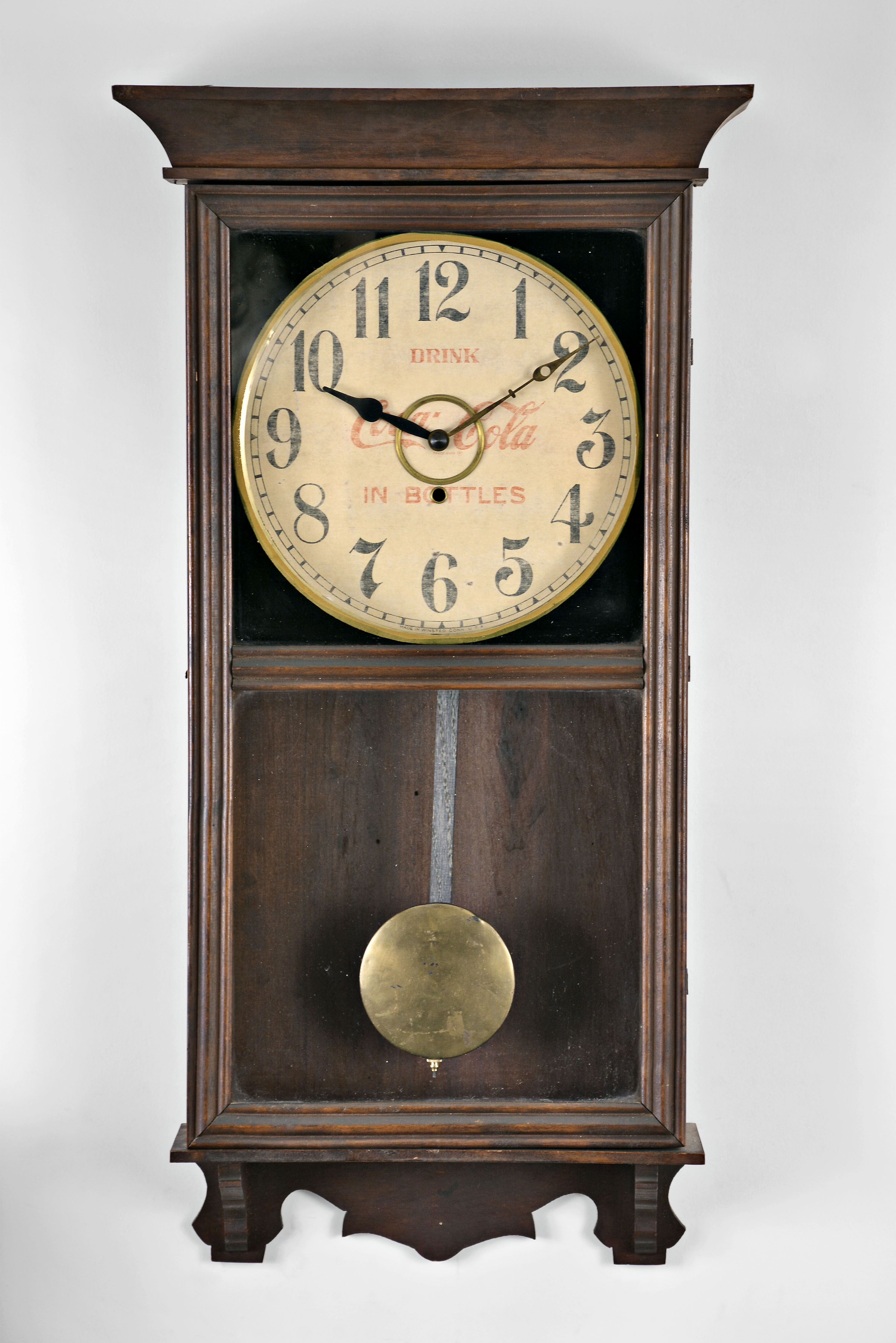 William L. Gilbert Clock Co., Winsted, Conn., "University" wall hanging store regulator with a spring driven 8 day timepiece movement with a 12" Coca Cola advertising dial in a wooden case with a polished mahogany finish. — Antique Clocks Price Guide