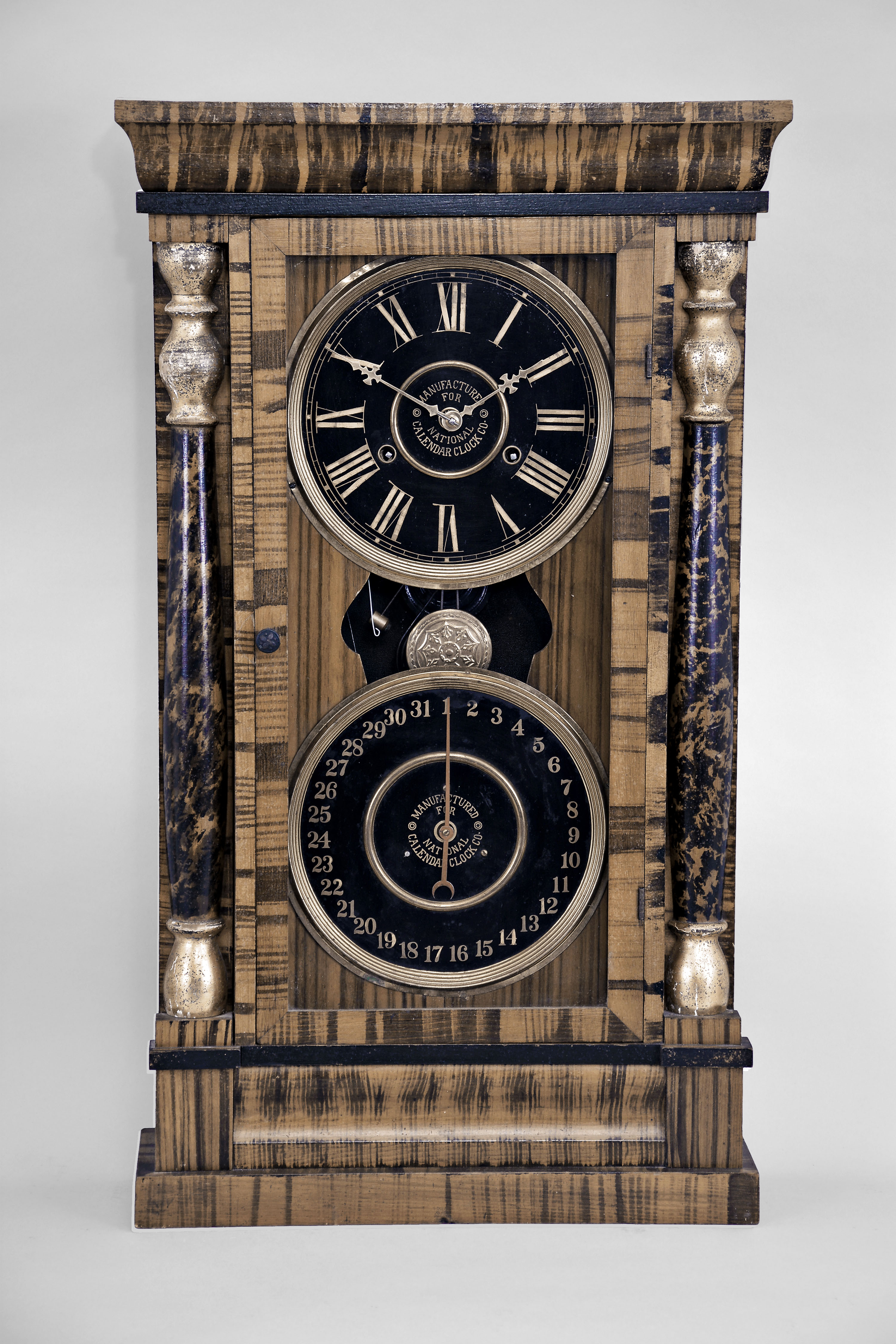 New Haven Clock Co. (For the National Calendar Clock Co.), New Haven, Conn, "Column Calendar Clock" with a spring driven 8 day time and strike movement with a simple calendar mechanism in a veneer imitation grained case with gilt capped faux painted tortoise shell columns. — Antique Clocks Price Guide