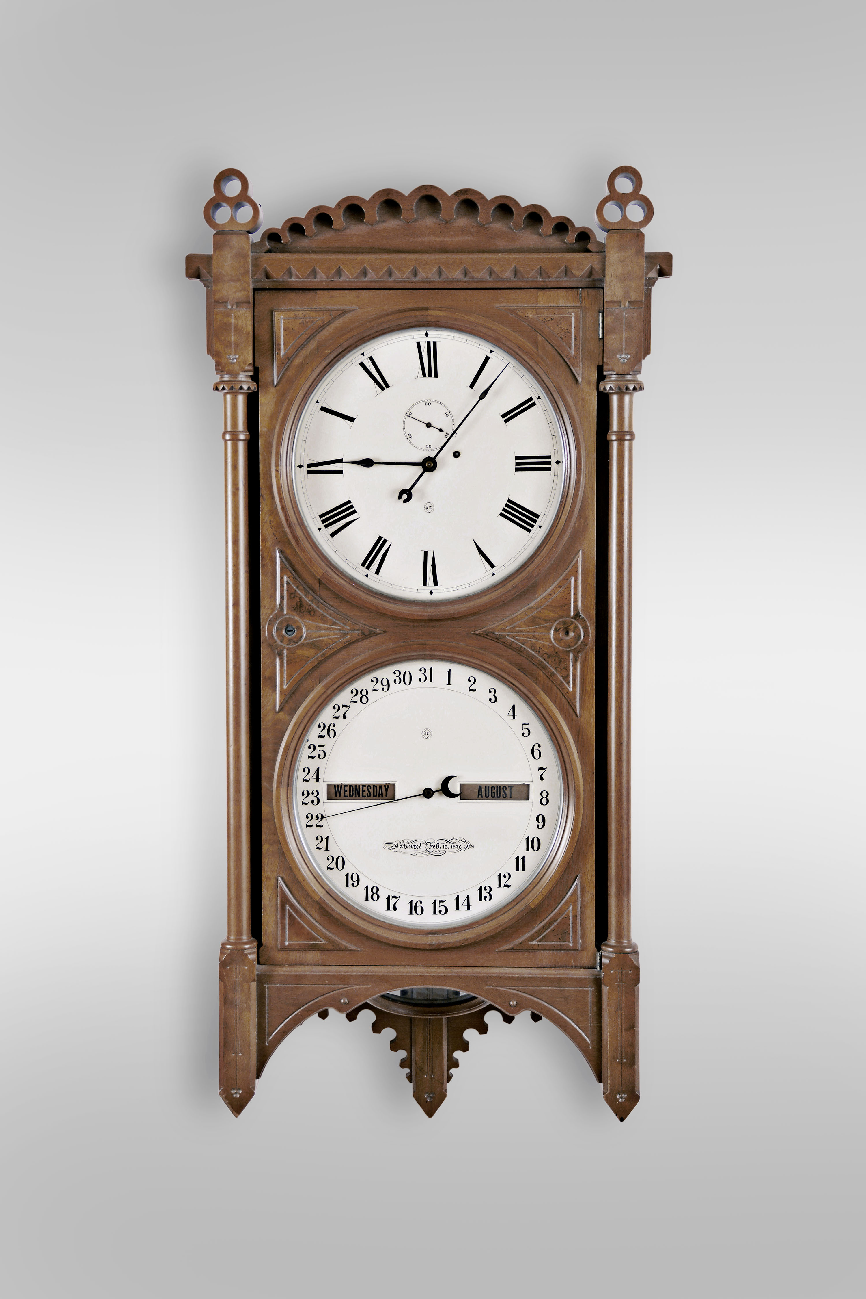 Seth Thomas Clock Co., Thomaston, Conn., "Office Calendar No. 5" wall clock, 8 day, weight driven movement with perpetual calendar in a walnut case with six burl spandrels on front door and lenticle for pendulum bob and painted metal dials — Antique Clocks Price Guide