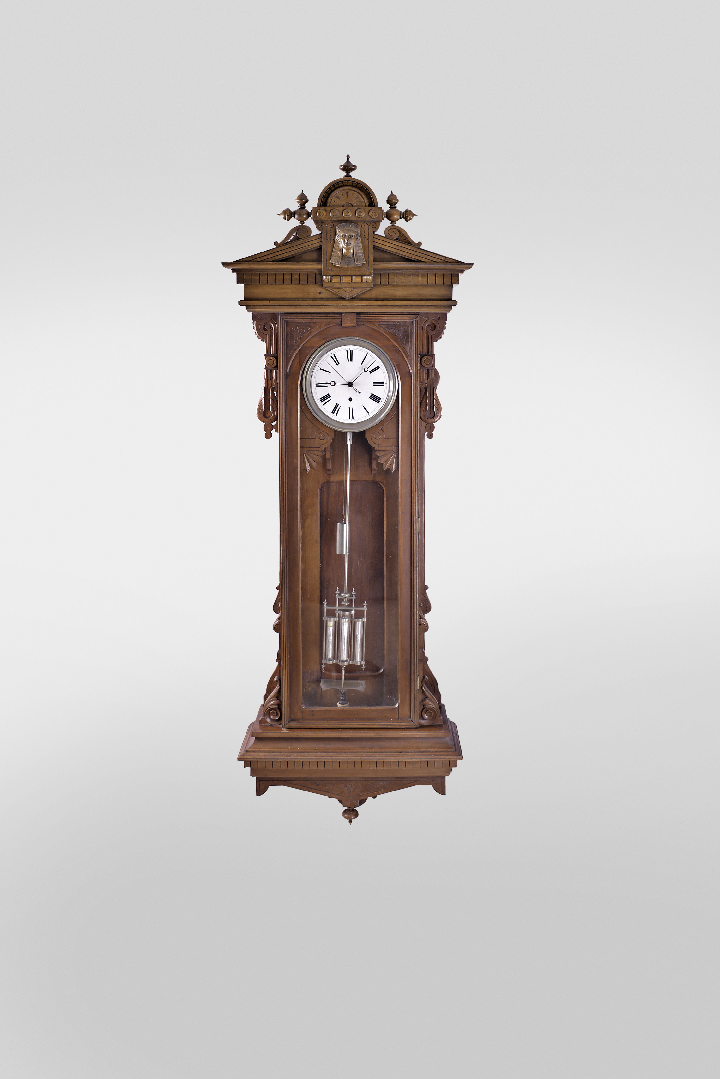 Wm. L. Gilbert Clock Co., Winsted, Conn., "Regulator No. 16 Hanging" jeweler's regulator, 8 day, time only, weight driven movement with deadbeat escapement, maintaining power, sweep seconds and three vial mercury pendulum in a cherry case with Egyptian mask on pediment and white enamel dial — Antique Clocks Price Guide