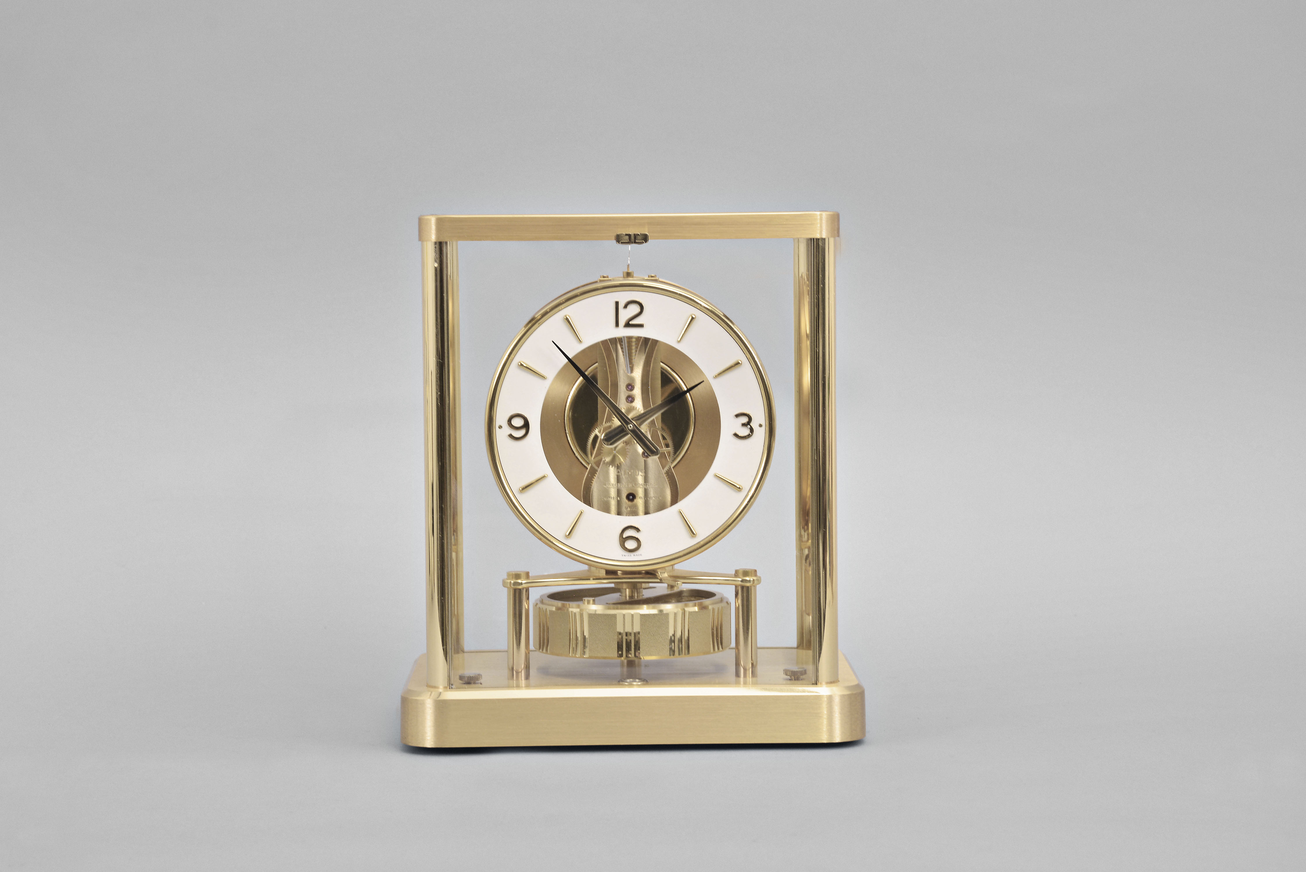 Jaeger-LeCoutre, Switzerland, "Atmos" clock, 13 Jewel, caliber 540 movement, gilt torsion pendulum, round white painted dial with applied gilt numbers and hour markers, gilt hands, all contained within a glazed rectangular case with flip-front door, movement serial number 630240. — Antique Clocks Price Guide