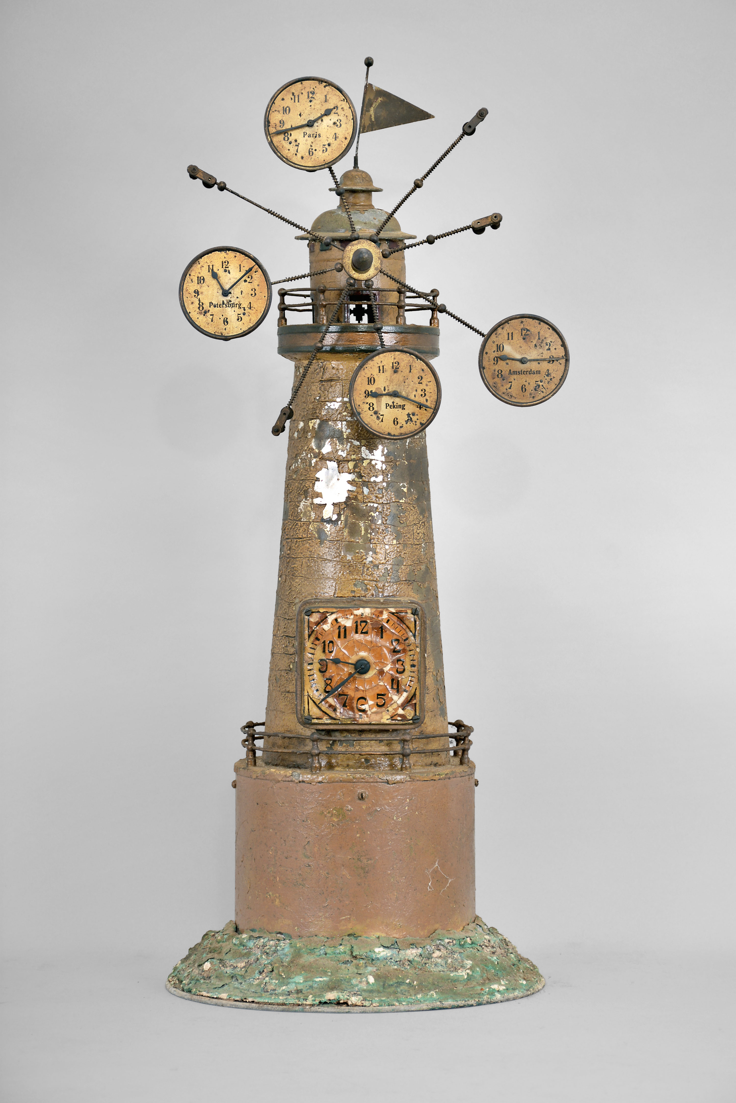 Gebruder Junghans AG, Schramberg, Germany, "World Time Clock", 8 day, time only, spring driven pendulum movement in a metal case taking the form of a windmill, a primary clock dial in the base and subsidiary dials radiating from the top showing times for other locations on the globe including Paris, Peking, Amsterdam, Petersburg. — Antique Clocks Price Guide