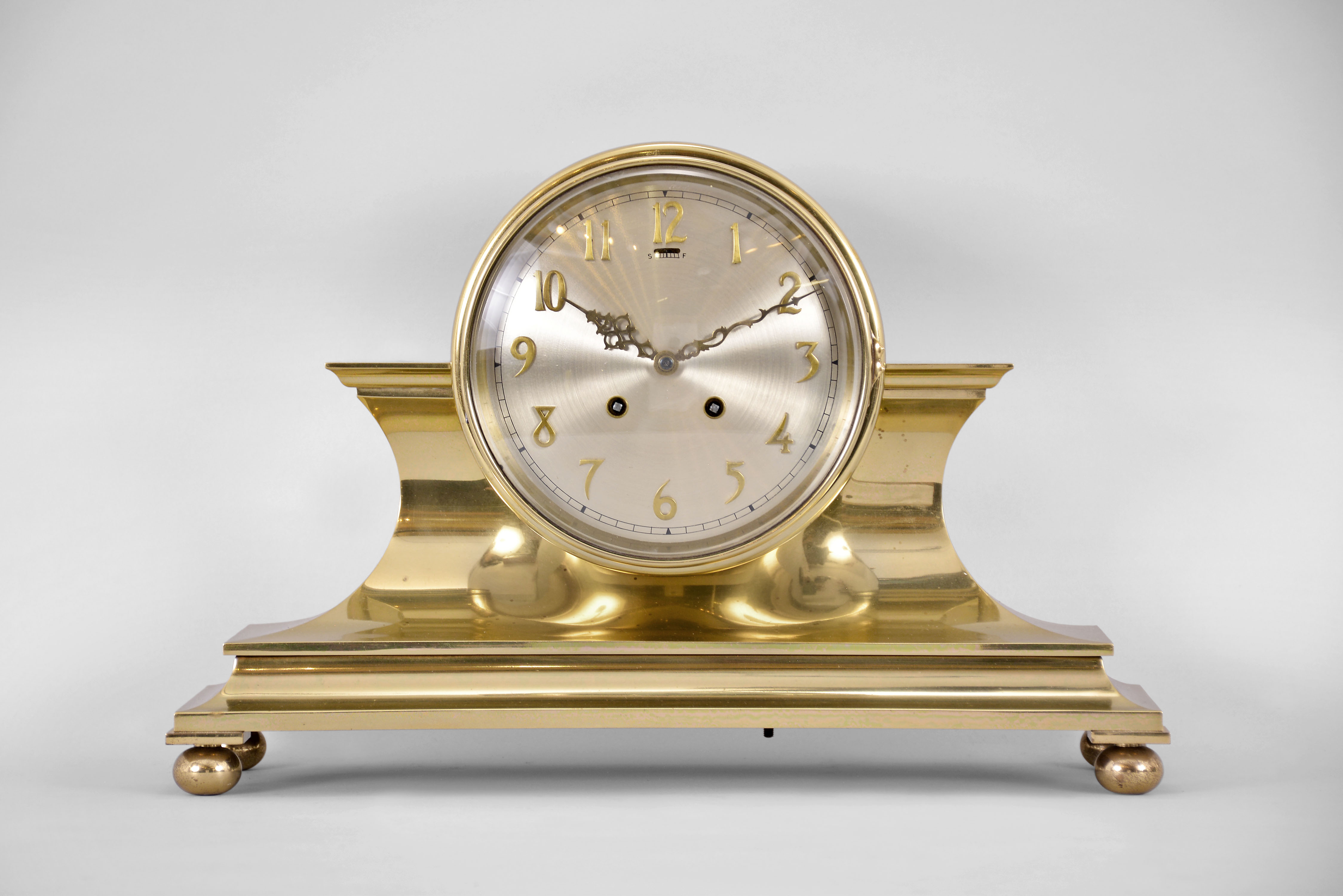 Chelsea Clock Co., Boston, Mass., "Tambour No. 1" mantel clock, 8 day, time and house strike, spring driven balance wheel movement with lever escapement in a polished brass case on ball feet with a six inch silvered dial and applied brass numerals. — Antique Clocks Price Guide