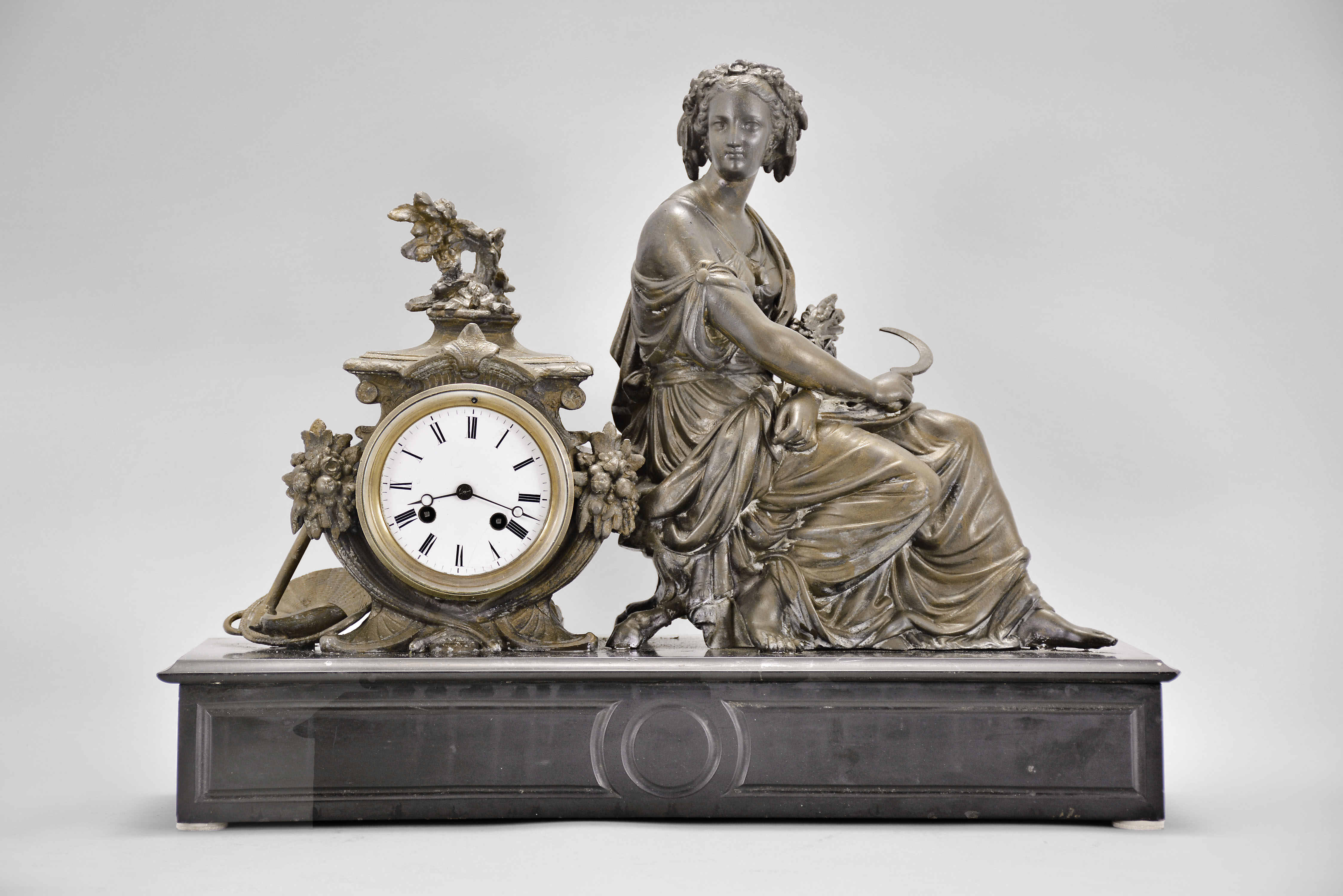 Japy Freres &amp; Cie, Paris, France, figural mantel clock, 8 day, time and strike, spring driven pendule de Paris movement, black slate base with molded front and top supporting a cast spelter case with agrarian theme including a basket and hoe, and seated female figure with a sickle in one hand and a sheaf of wheat in the other, white enamel dial with Roman numerals, and blued steel Breguet hands. — Antique Clocks Price Guide