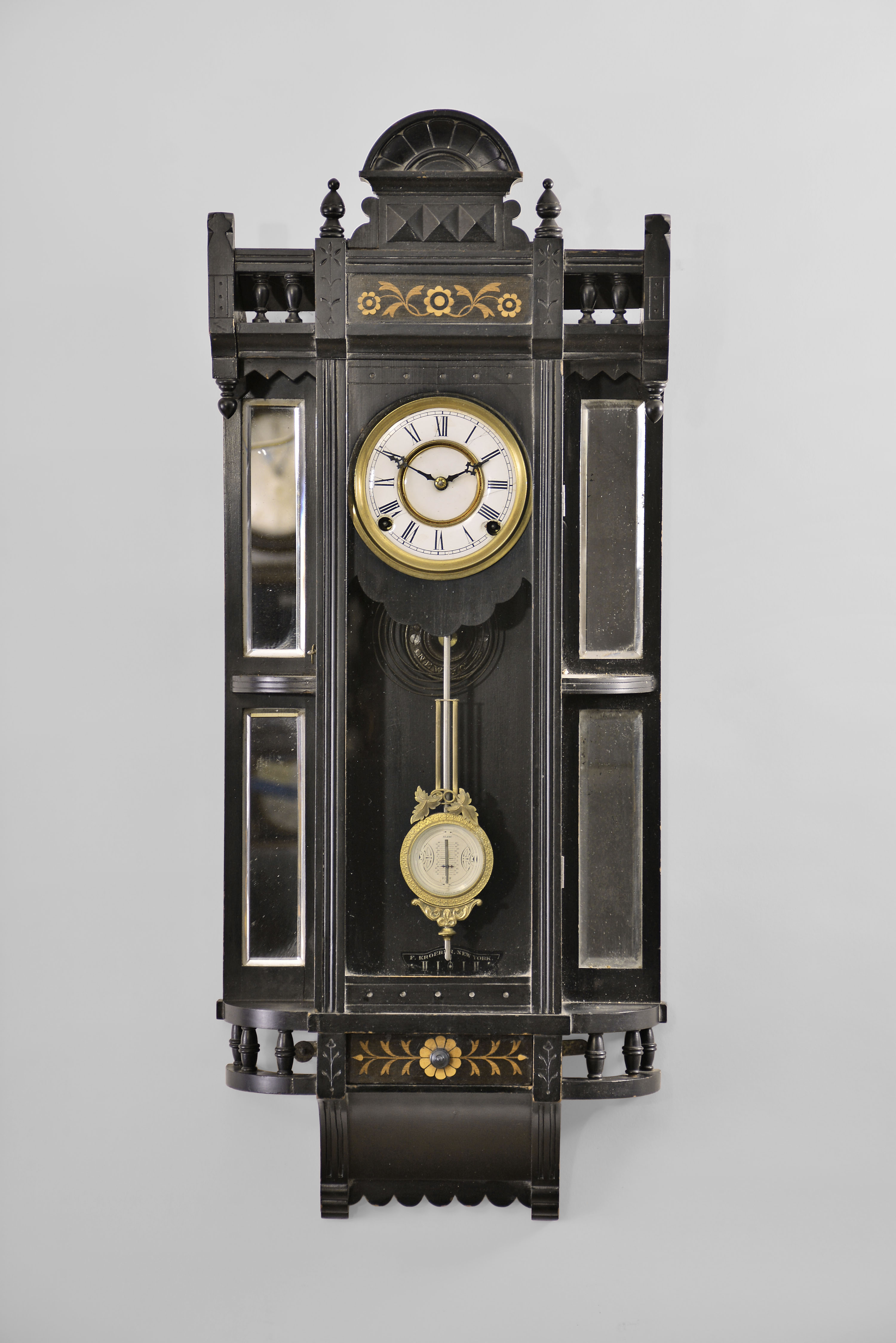 F. Kroeber Clock Co., New York, "Parthia" wall clock with a spring driven 8 day time and strike movement in an ebony case with real marquetries and beveled mirror sides. — Antique Clocks Price Guide