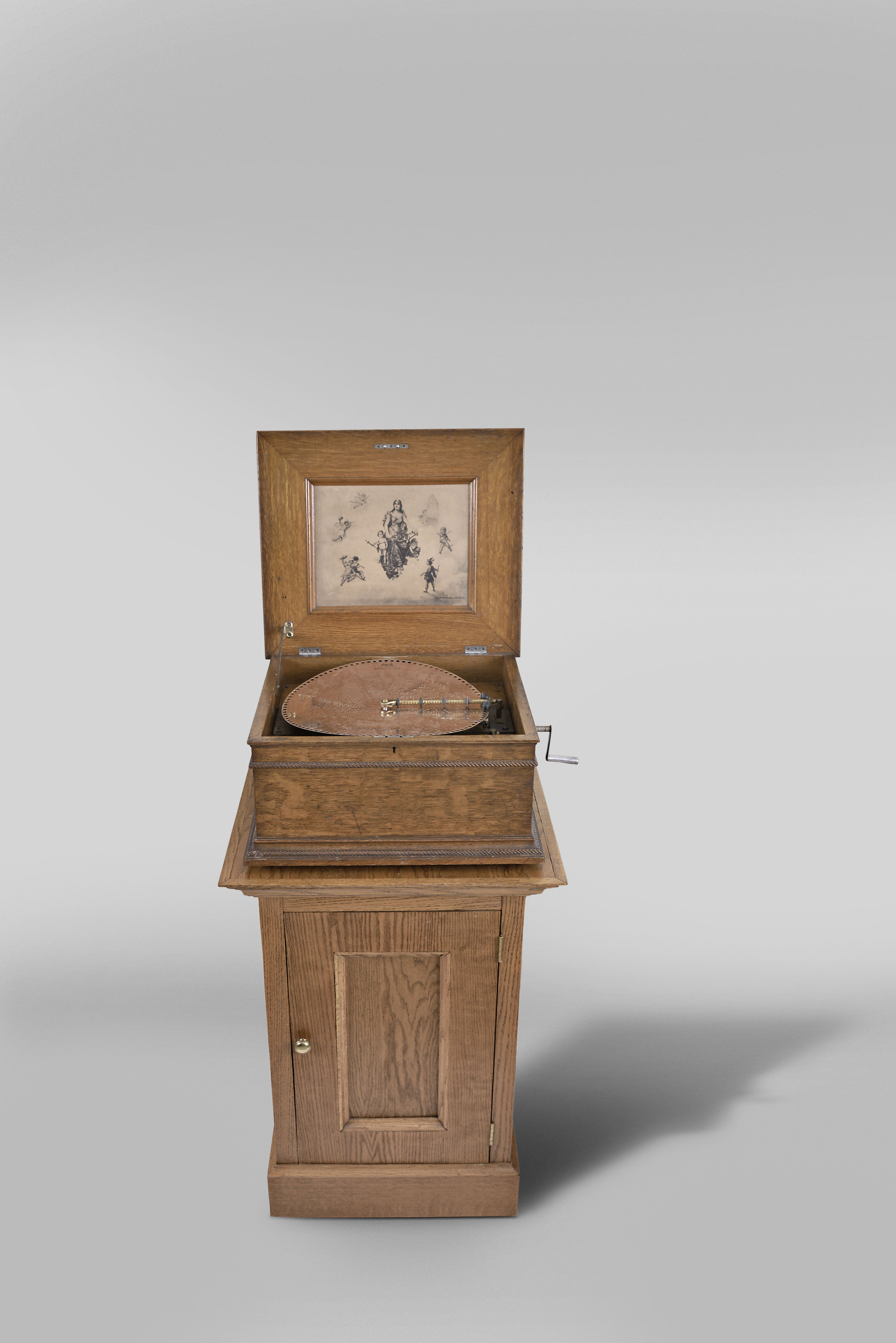 Regina Musical Box Co., Rahway, N.J., "Style 11A" 15.5 inch double comb music box with 10 discs, oak case with stepped ogee base and locking drawer, rope molding, stepped, molded lid, the inside with music-themed Regina lithograph including a custom made oak cabinet to support box and store discs (45 included) — Antique Clocks Price Guide