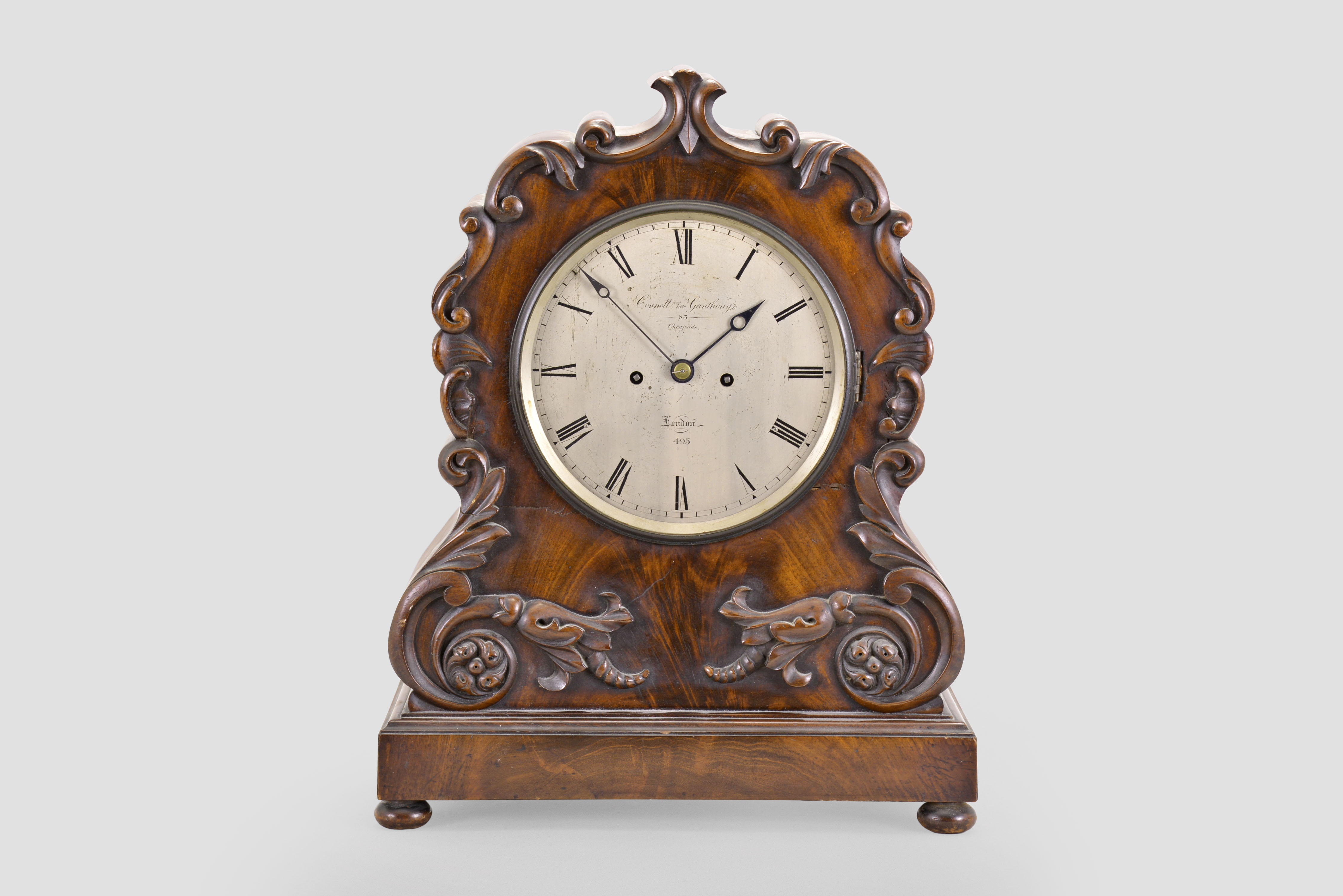 Connell, Late Ganthony, 83 Cheapside, London, a large, mid 19th century mahogany bracket clock, rectangular molded base with compressed ball feet, the case front with applied carved foliate ornaments with scrolls terminating in pendant husks, and with carved C and S scrolls flanking and above the silvered roman numeral dial, the case sides conforming to the contours of the carved elements, back with fabric lined door and fine mahogany fret, blued steel pierced spade hands, two train fusee movement with recoil escapement, counting the hours on a bell — Antique Clocks Price Guide