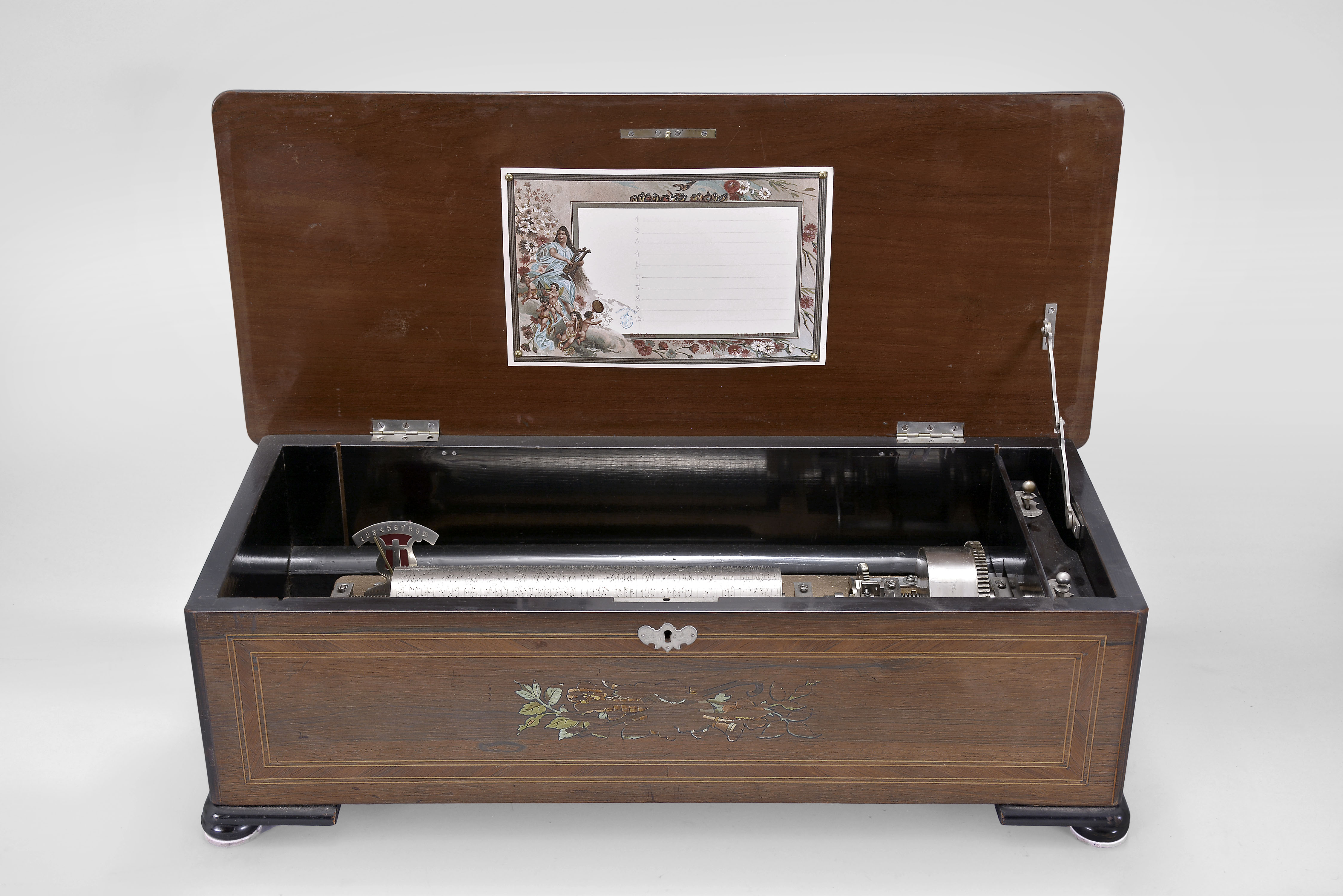 Switzerland, music box, playing 10 tunes with a 11 inch cylinder on a comb with 62 teeth in a grain painted wood case having a rosewood top with tinted inlay with musical trophy motif. — Antique Clocks Price Guide