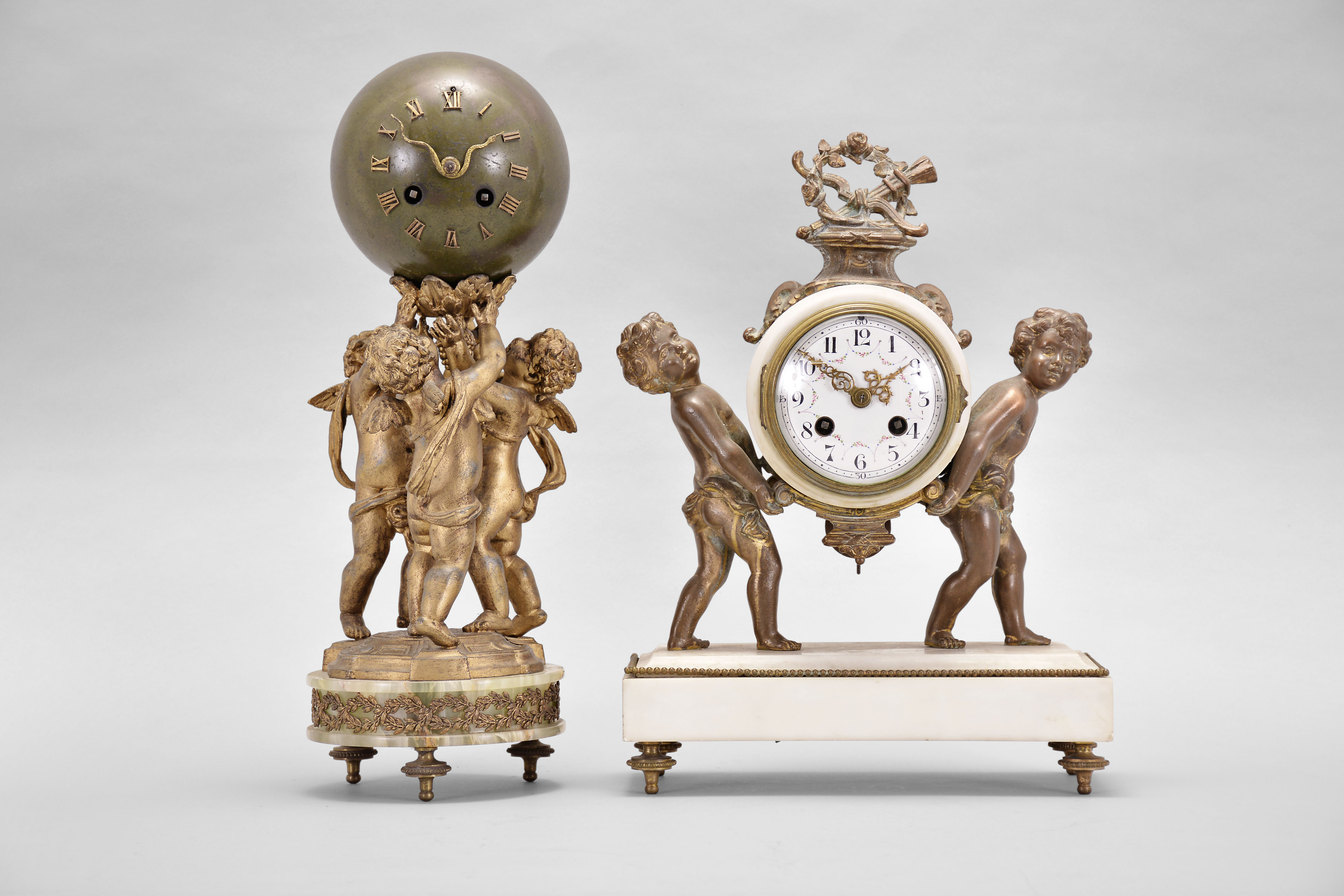 Clocks- 2 (Two) French mantel: (1) Samuel Marti, Paris, for A. Thelot, figural mantel clock, 8 day, time and strike, spring driven pendule de Paris movement, white marble case on brass feet with two cast child figures supporting a white marble case between them, white enamel dial with polychrome garlands and Arabic numerals, gilt hands, c1900; (2) France, figural mantel clock, 8 day, time and strike, spring driven pendule de Paris movement, green onyx base on cast brass feet, supporting three putti holding a green patinated sphere and the mechanism within aloft, applied Roman numerals and gilt snake-form hands, c1915. — Antique Clocks Price Guide