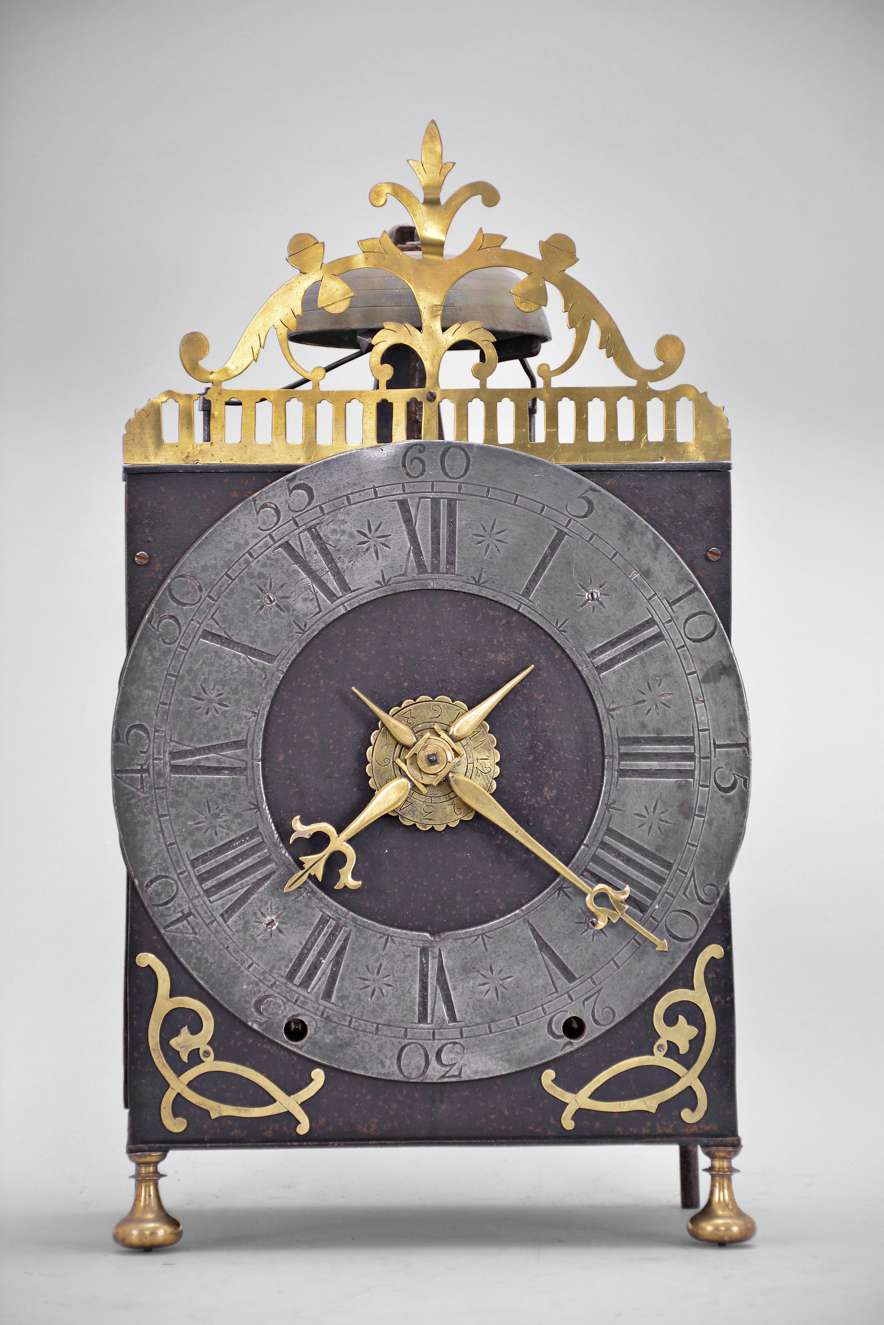 France, oversized Comtoise lantern clock, month running, time and strike with alarm, weight driven movement with verge escapement, rear-mounted thread suspension in a iron post and plate frame with turned brass feet in the front, pewter chapter ring with Roman numerals for the hours, outer ring with Arabic numerals every 5 minutes, brass alarm ring with Arabic numerals, pierced flat brass fronton and lower spandrels, and two brass hands. — Antique Clocks Price Guide