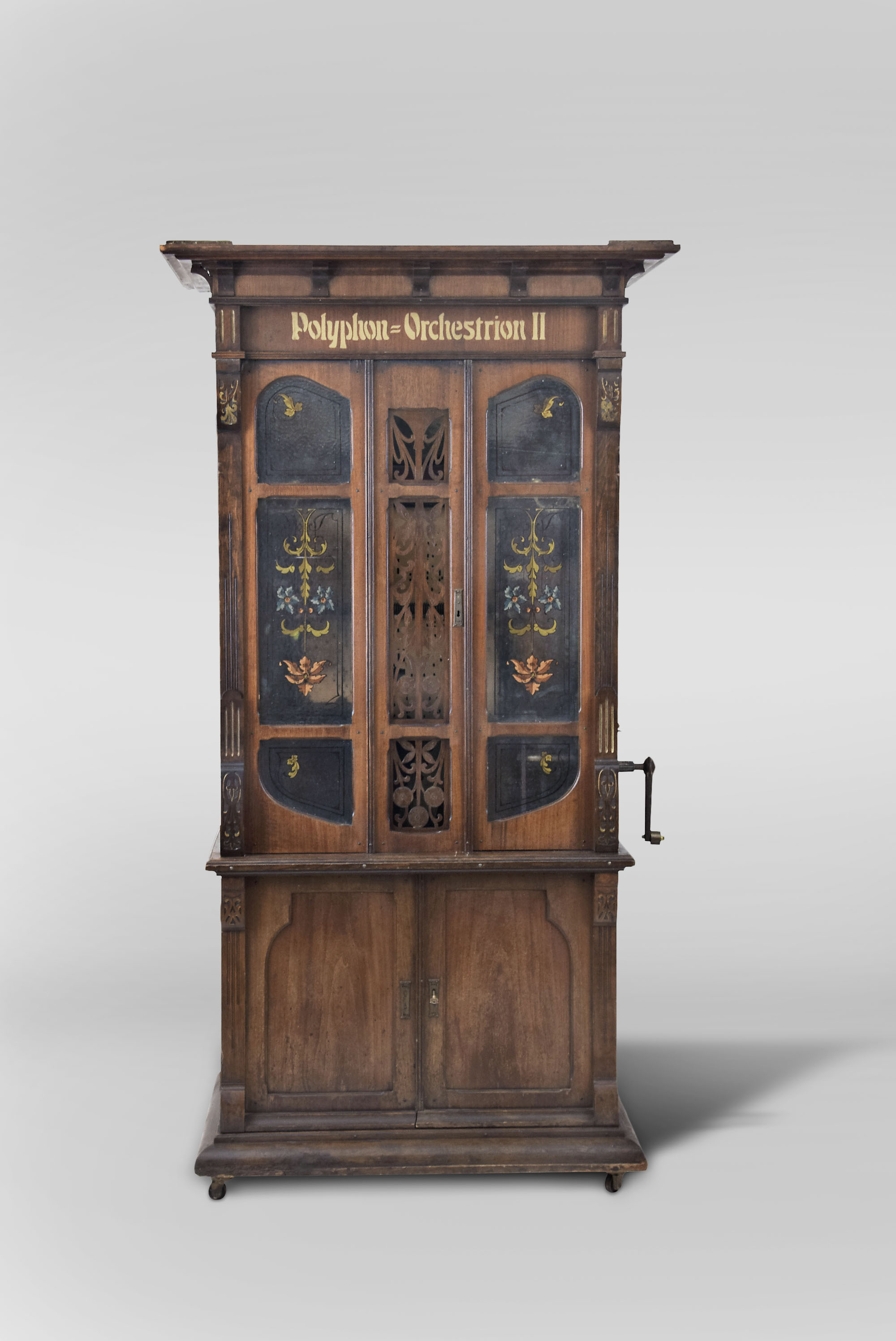 Polyphon Musikwereke, Leipzig, Germany, "Polyphon Orchestrion II" or "Polyphon Rossini" Upright Music Box, piano with drum and trap effects model, coin operated, weight driven, playing 73 note cylinder rolls containing 3 tunes each, in a mahogany case with reverse painted frosted glass doors above and cabinet with two doors below resting on four casters — Antique Clocks Price Guide