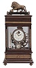 Reproduction Ferris wheel gravity timepiece, 8 day, time only, weight driven balance wheel movement in a glazed wood case with applied brass ornaments, polychrome enamel dial, a small barometer dial below, and alcohol thermometer adjacent, all surmounted by a patinated brass lion.
