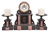 Fritz Marti et Fils, Vieux-Charmont, France, three piece mantel garniture, 8 day, time and strike, spring driven pendule de Paris movement with visible Brocot escapement and compensating pendulum in a black slate case with variegated red marble columns and accents, white two-piece enamel dial, beveled glasses, and blued steel hands with two matching tazze and candles.
