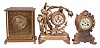 Clocks- 3 (Three): (1) Ansonia Clock Co., New York, NY, "Kensington" mantel clock, 8 day, time and strike, spring driven movement in a brass case with a brass dial, c1901; (2) Waterbury Clock Co., Waterbury, Conn., mantel clock, 8 day, time and strike, spring driven movement in a gilt brass case, c1910; (3) Wm. L. Gilbert Clock Co., Winsted, Conn., figural mantel clock, 8 day, time and strike, spring driven movement with Brocot escapement in a cast metal case with three incandescent bulbs, c1915.
